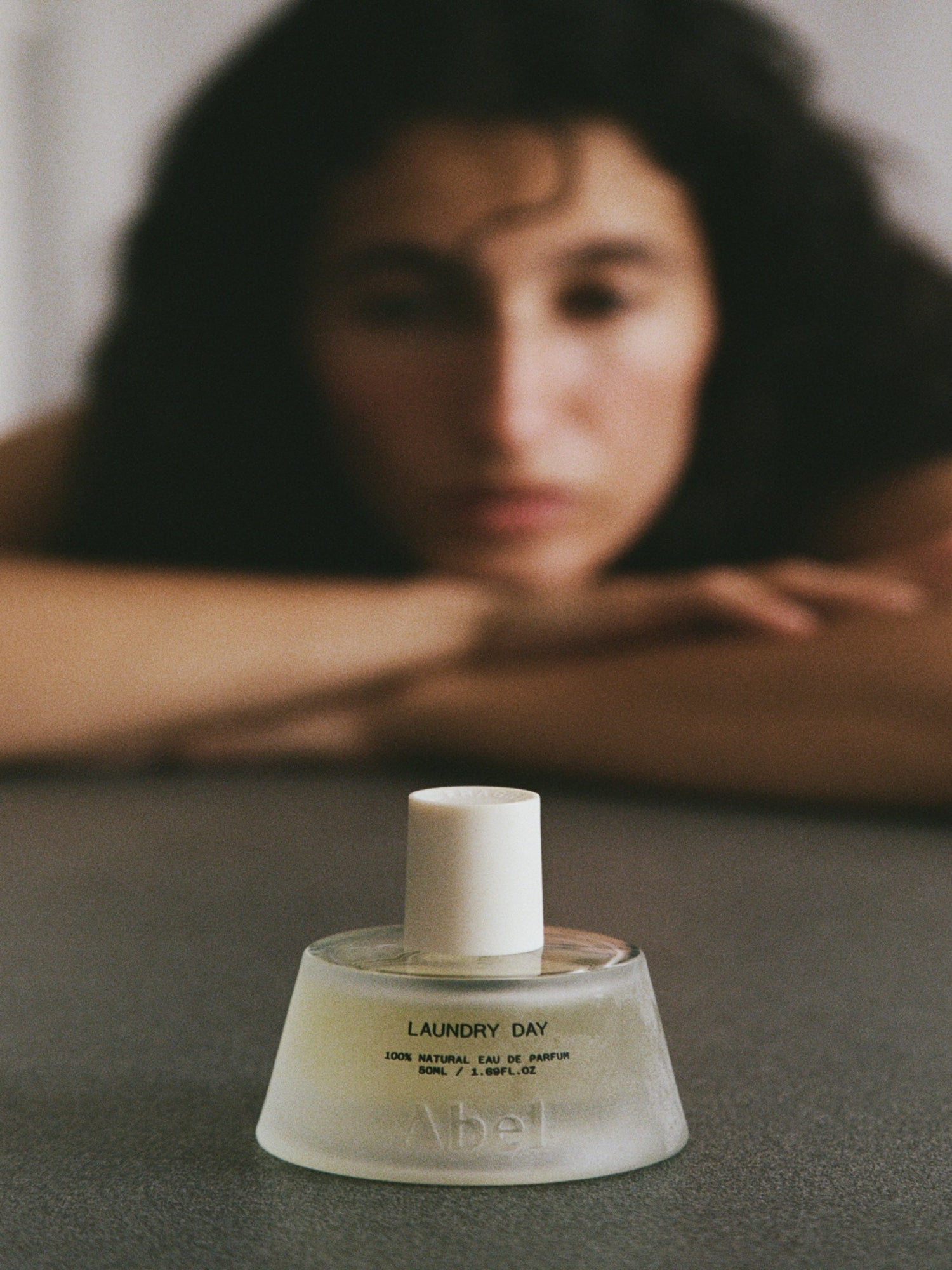Abel Laundry Day natural eau de parfum bottle with model in soft focus background