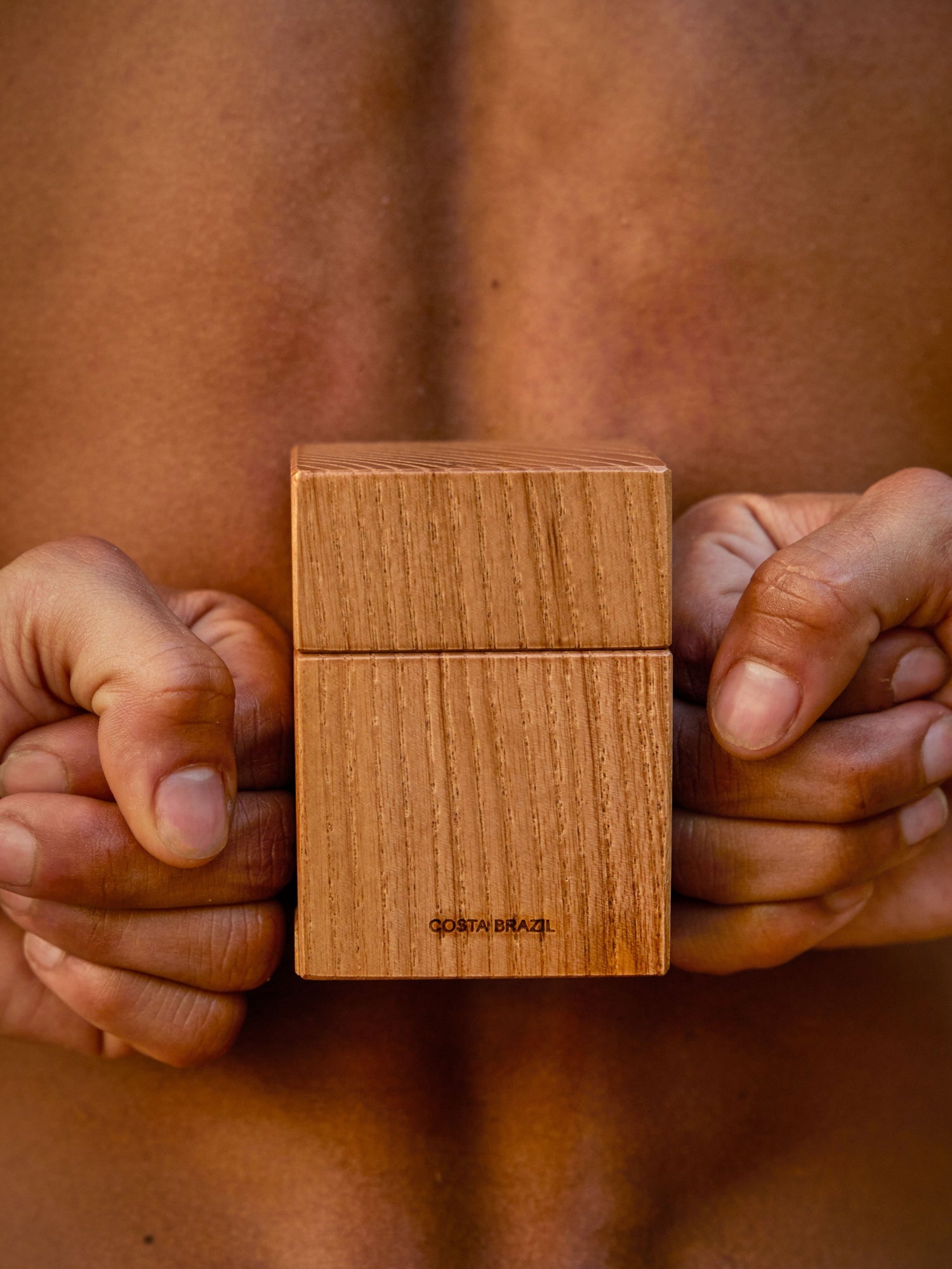 COSTA BRAZIL Aroma Eau de Parfum – lifestyle image of the wooden fragrance bottle held against bare skin