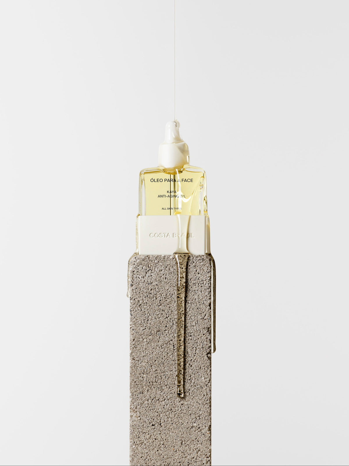 Costa Brazil Oleo Para Face Kaya Anti-Aging Face Oil – facial oil bottle on a stone pedestal with oil dripping down
