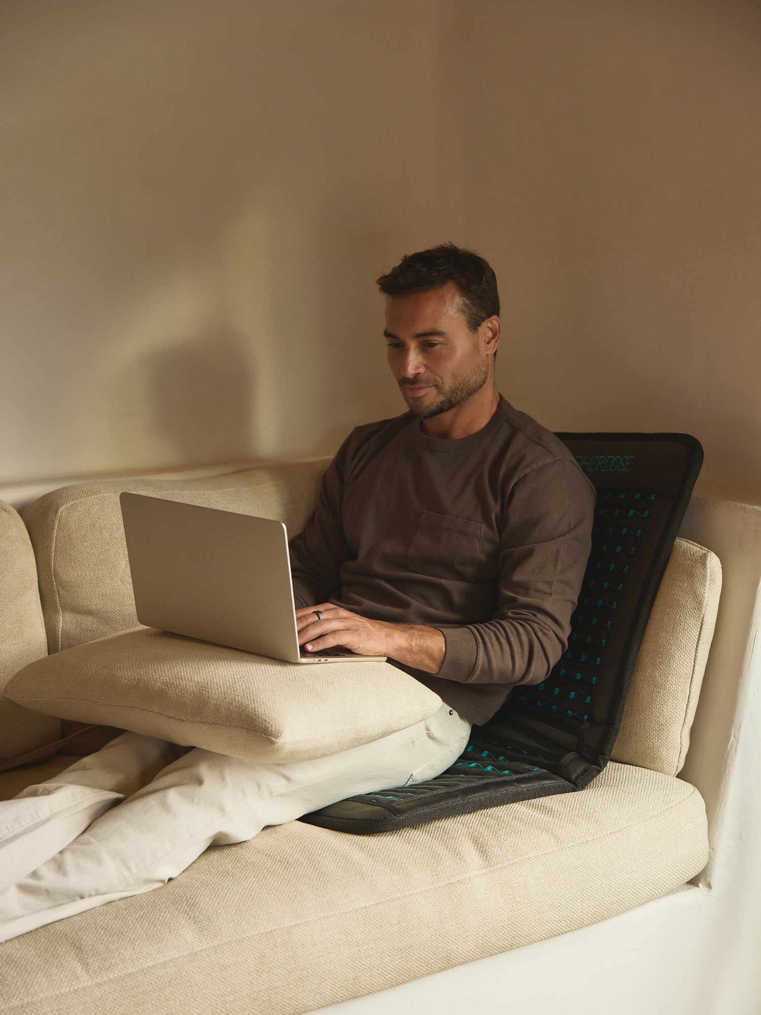 HIGHERDOSE Infrared PEMF Go Mat with man using the mat while working on a laptop