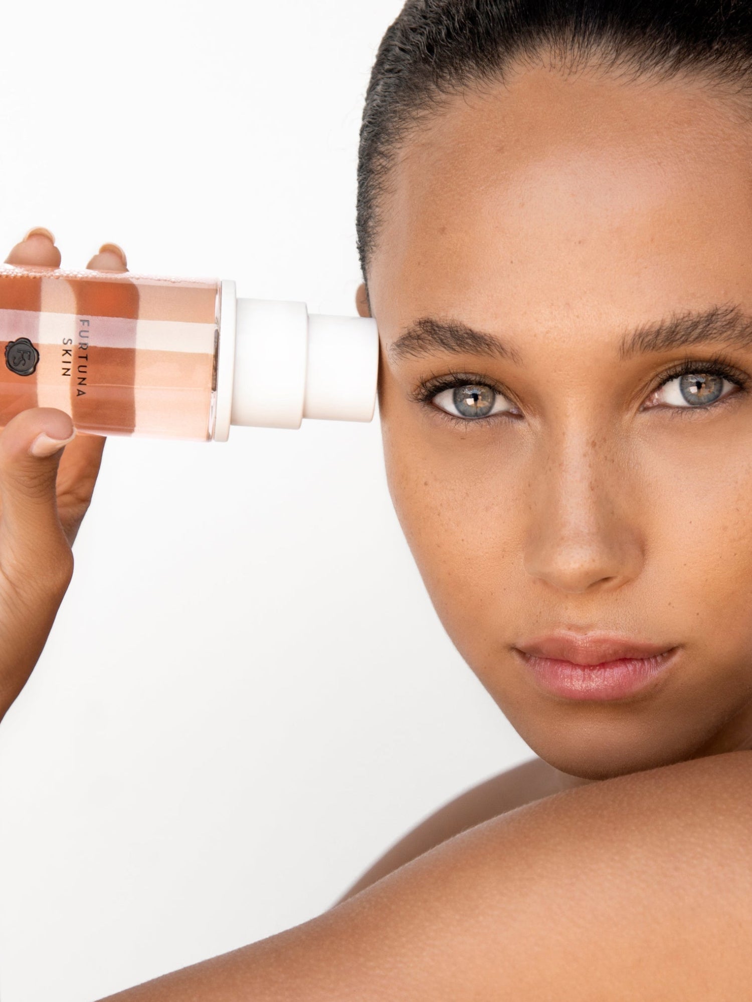 Furtuna Skin Micellar Cleansing Essence held beside model's face