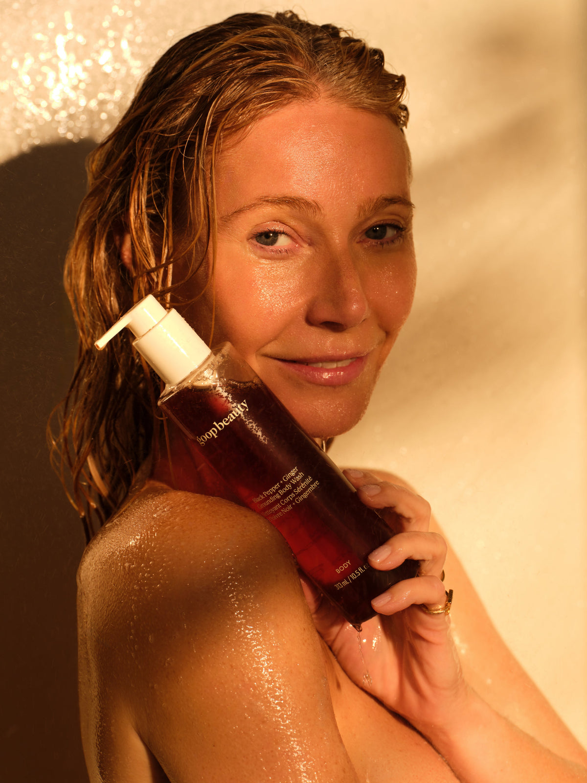 Model holding goop beauty Black Pepper + Ginger Grounding Body Wash