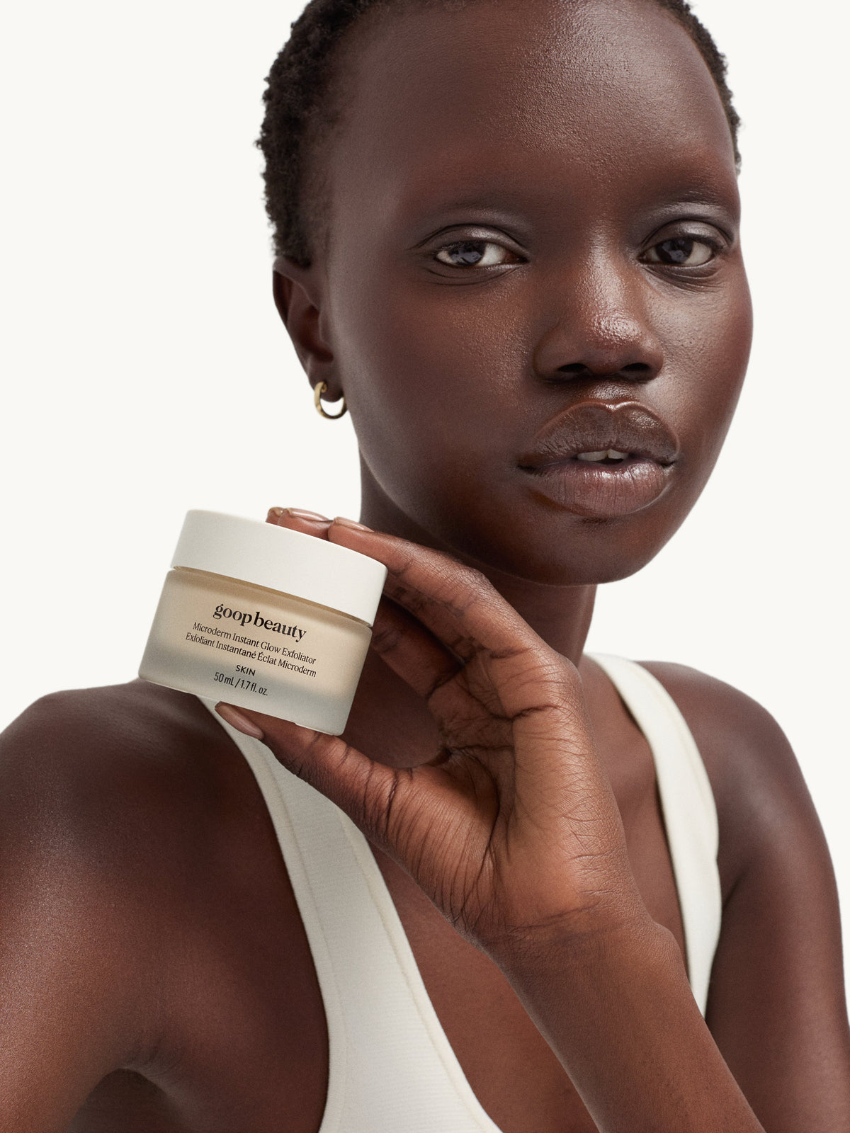 Model holding goop Microderm Instant Glow Exfoliator facial exfoliator