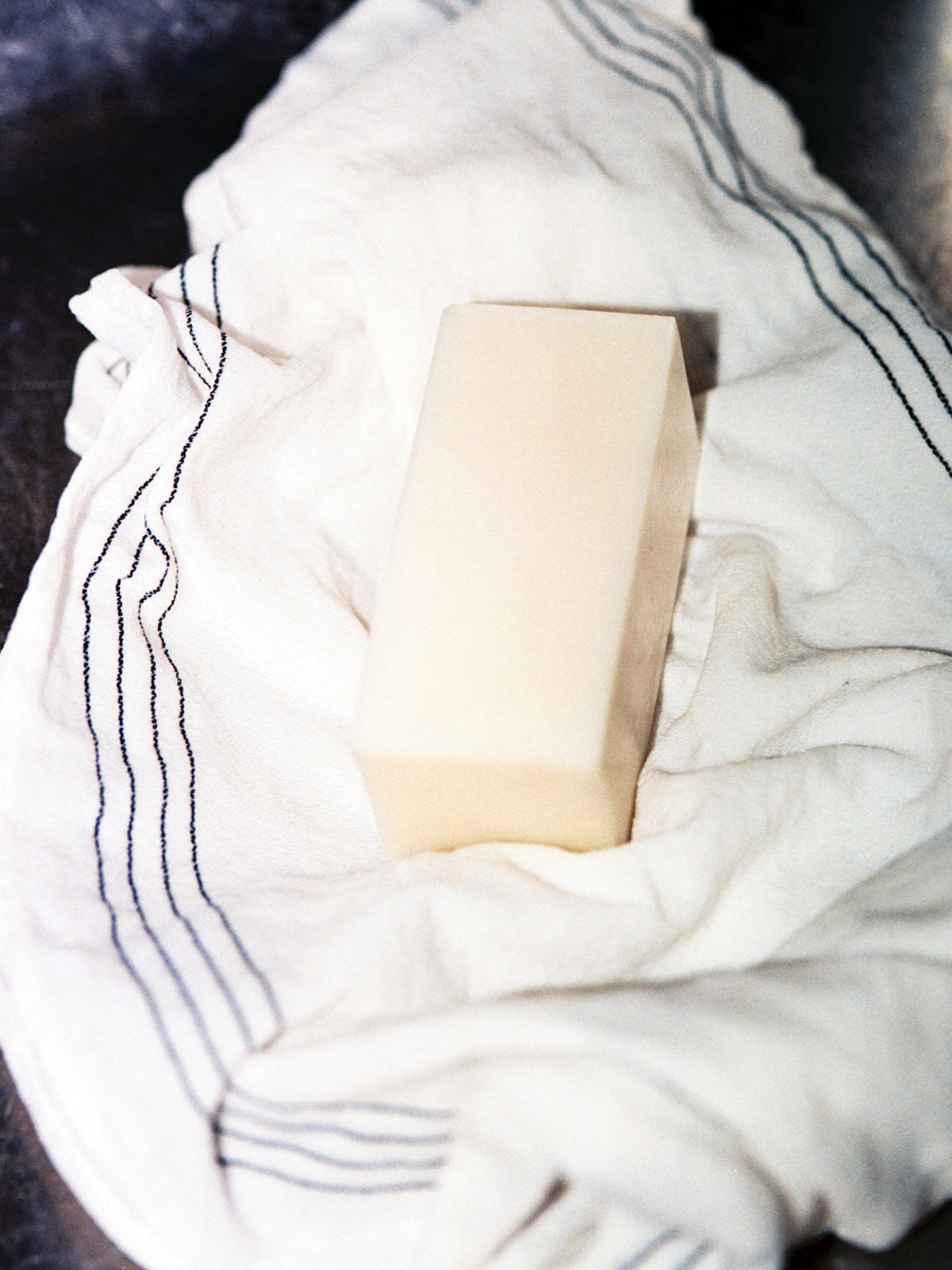 Jjimjil Aegi Super Mild Soap bar displayed on a soft white towel with dark stripes