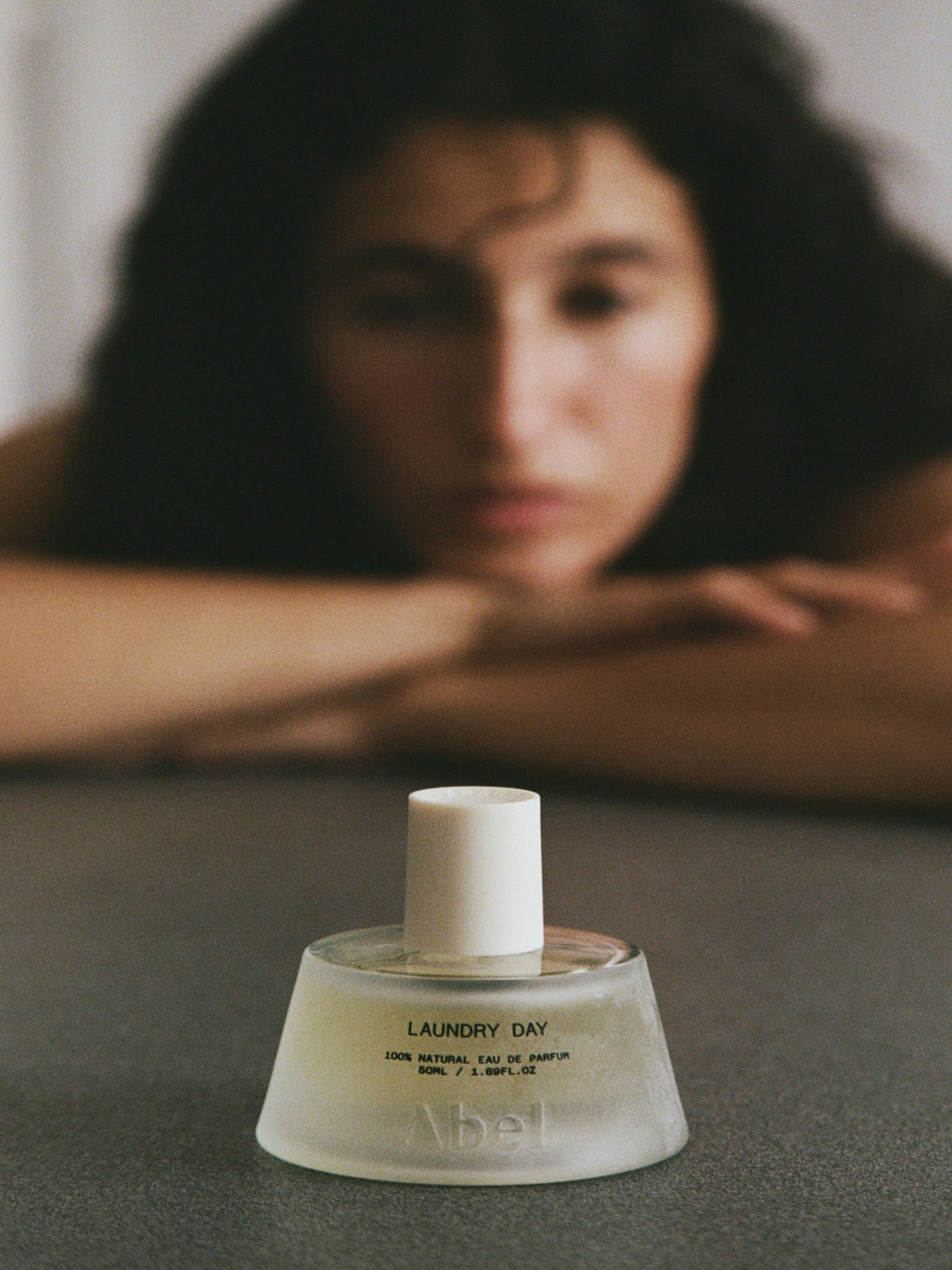 Abel Laundry Day natural eau de parfum bottle with model in soft focus background