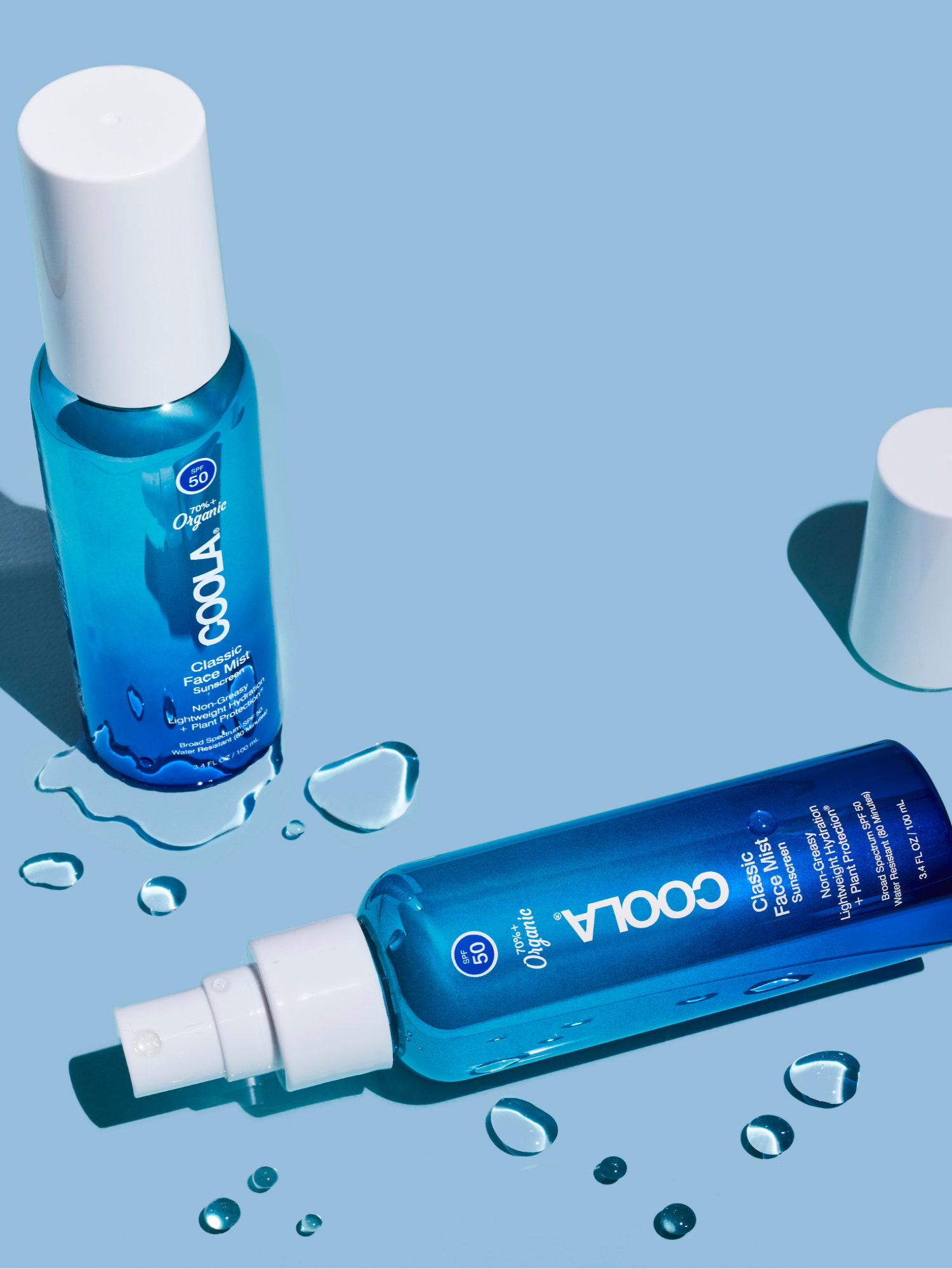 COOLA Classic Face Mist SPF 50 and Face Mist SPF 30 bottles with water droplets