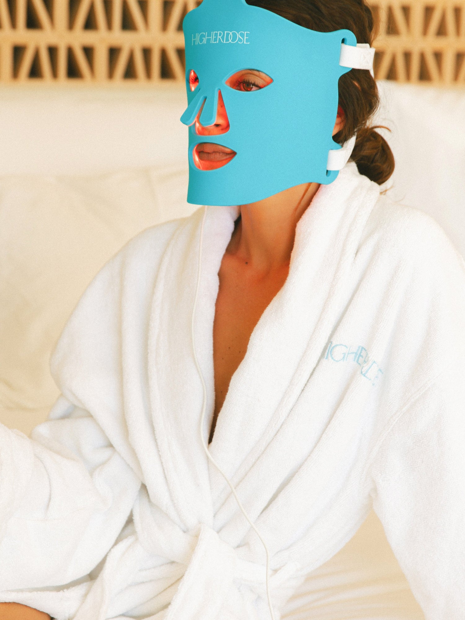 HIGHERDOSE Red Light Face Mask worn by woman in white bathrobe
