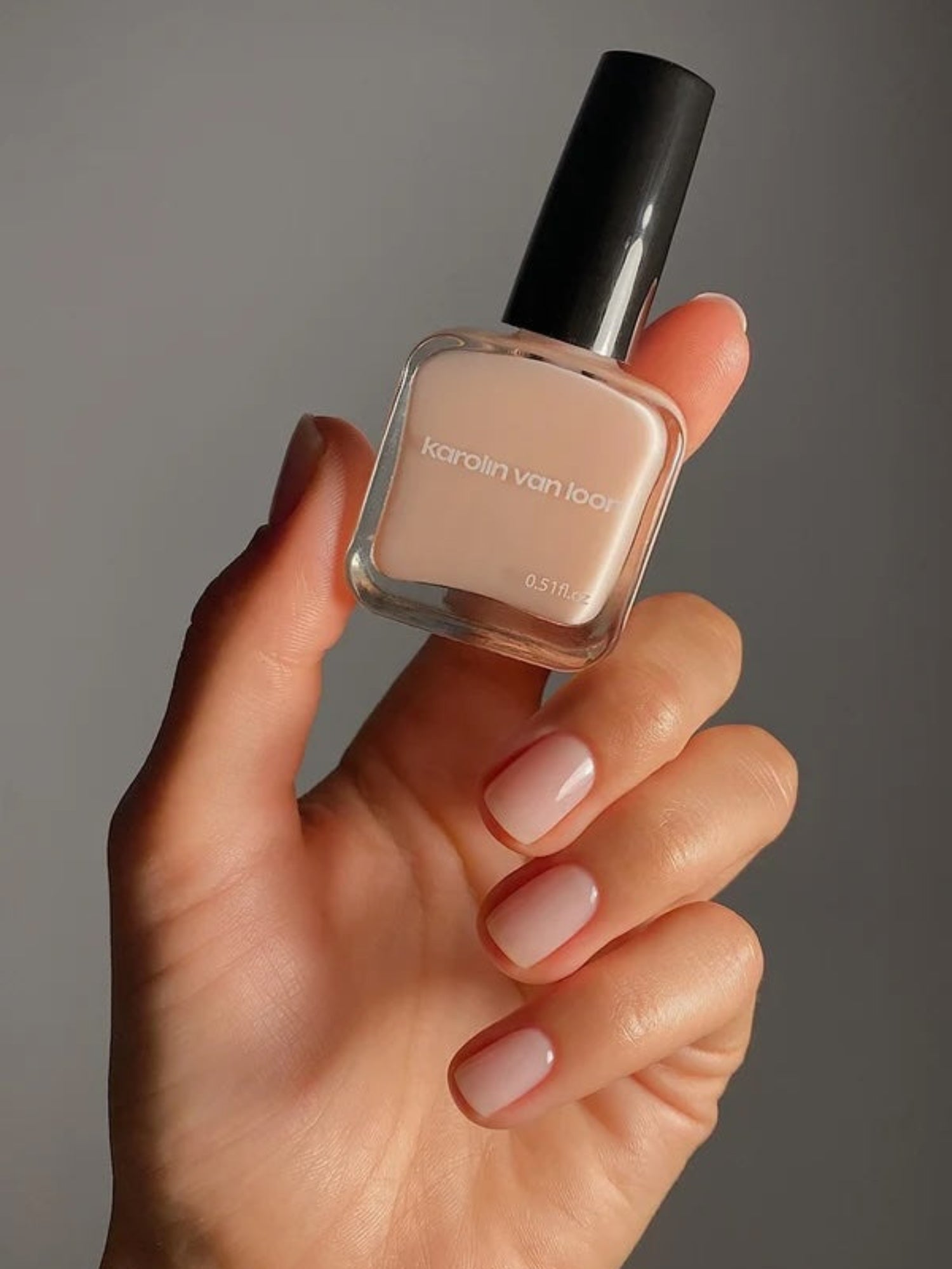 KAROLIN VAN LOON La Première Base Coat nail polish bottle in hand