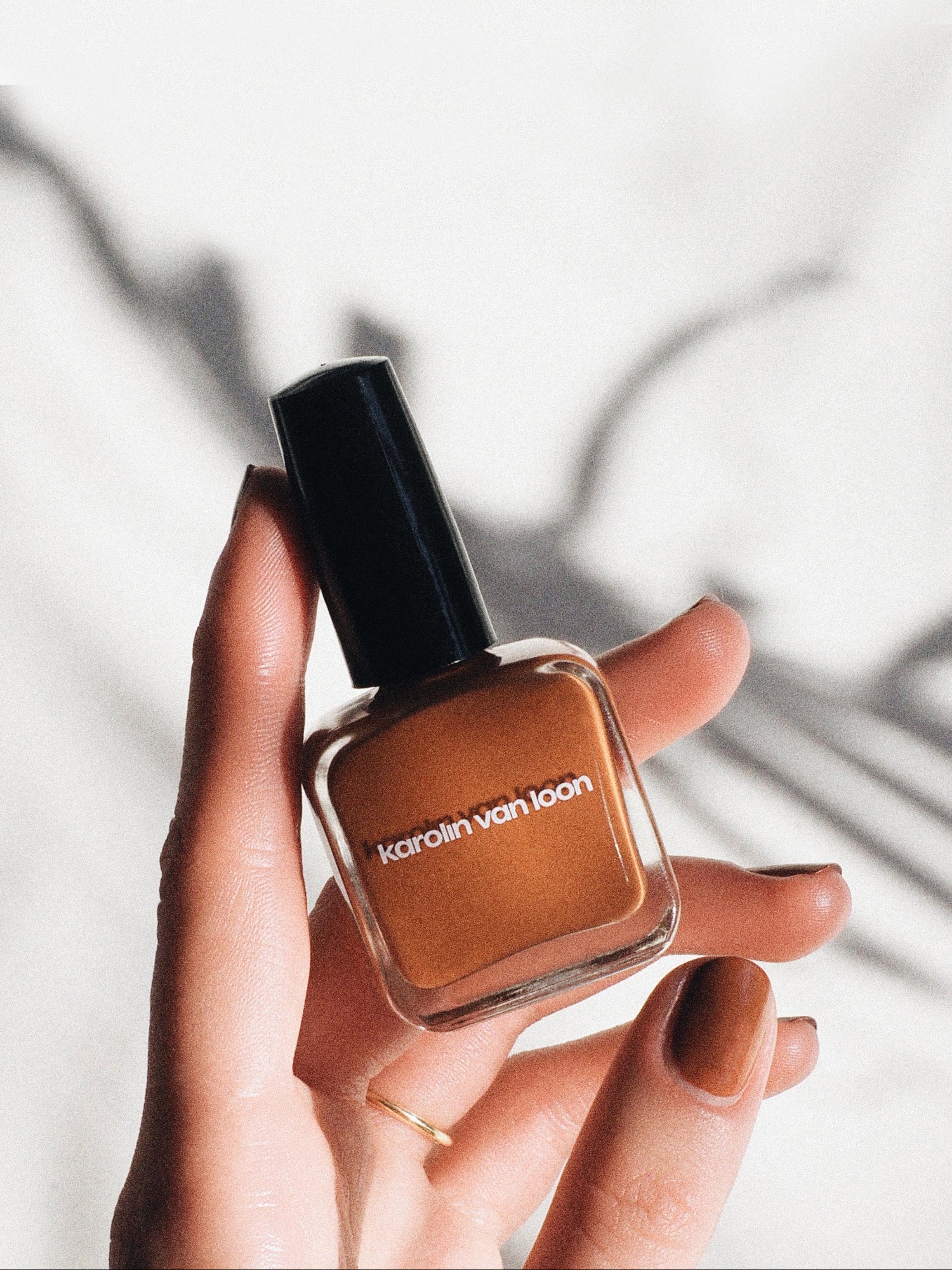 Hand holding Karolin Van Loon Tulip Orange nail polish lifestyle image