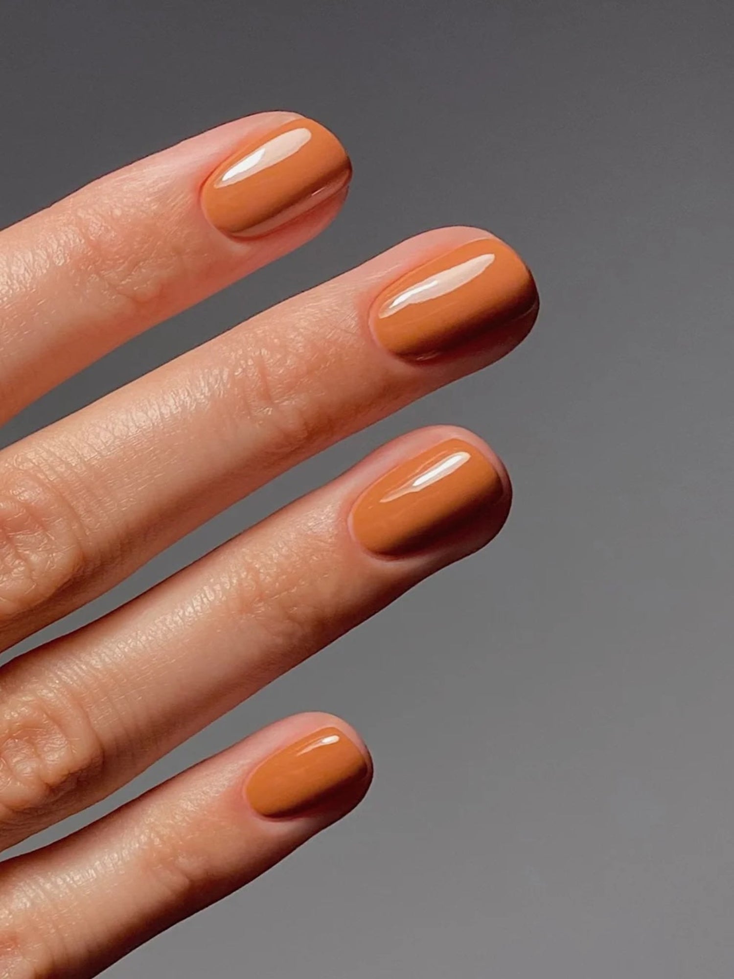 Model wearing Karolin Van Loon Zinia Orange Nail Polish