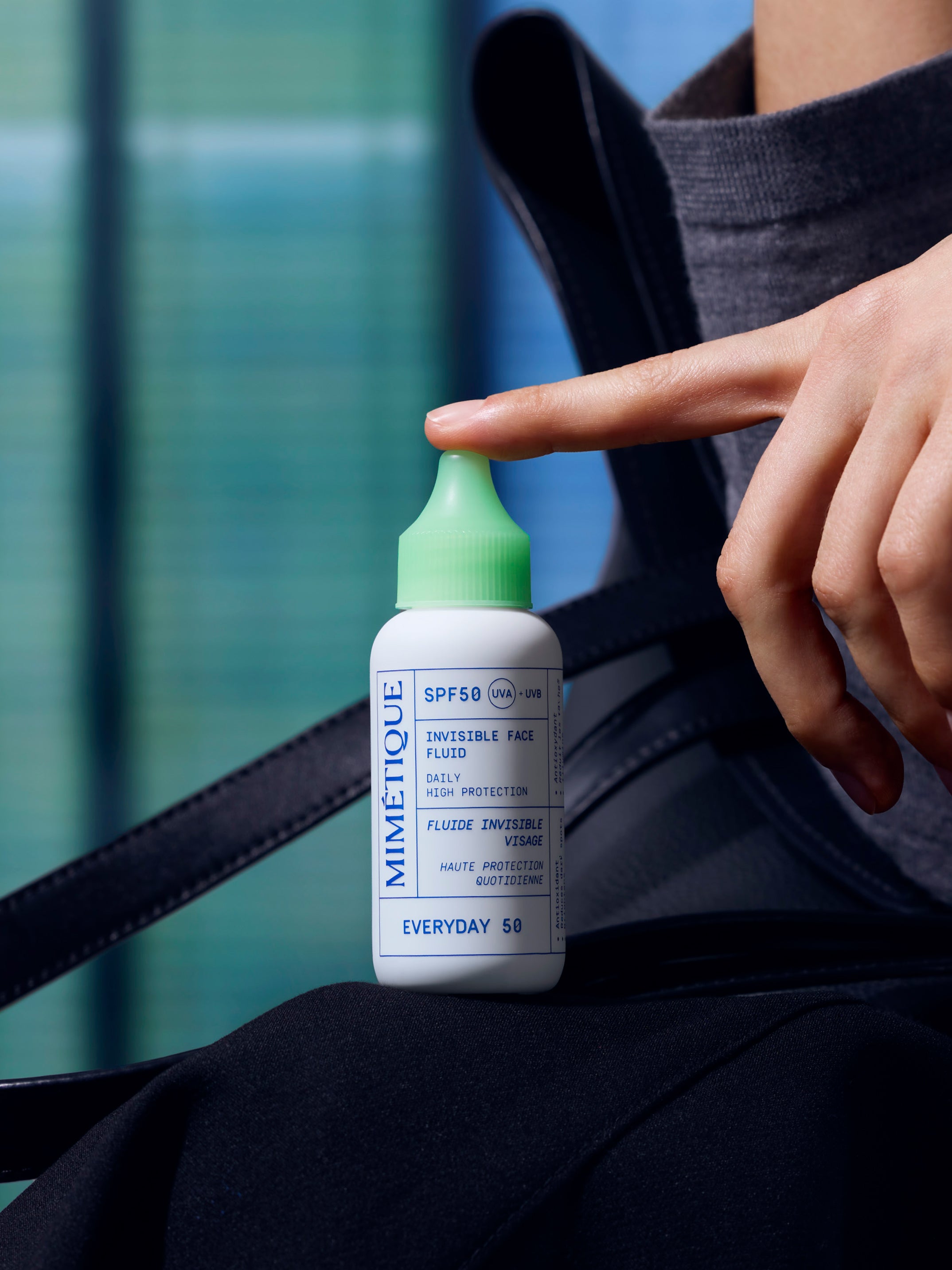 Bottle of MIMÉTIQUE Everyday 50 Invisible Face Fluid SPF50 UVA + UVB posed on a trouser leg