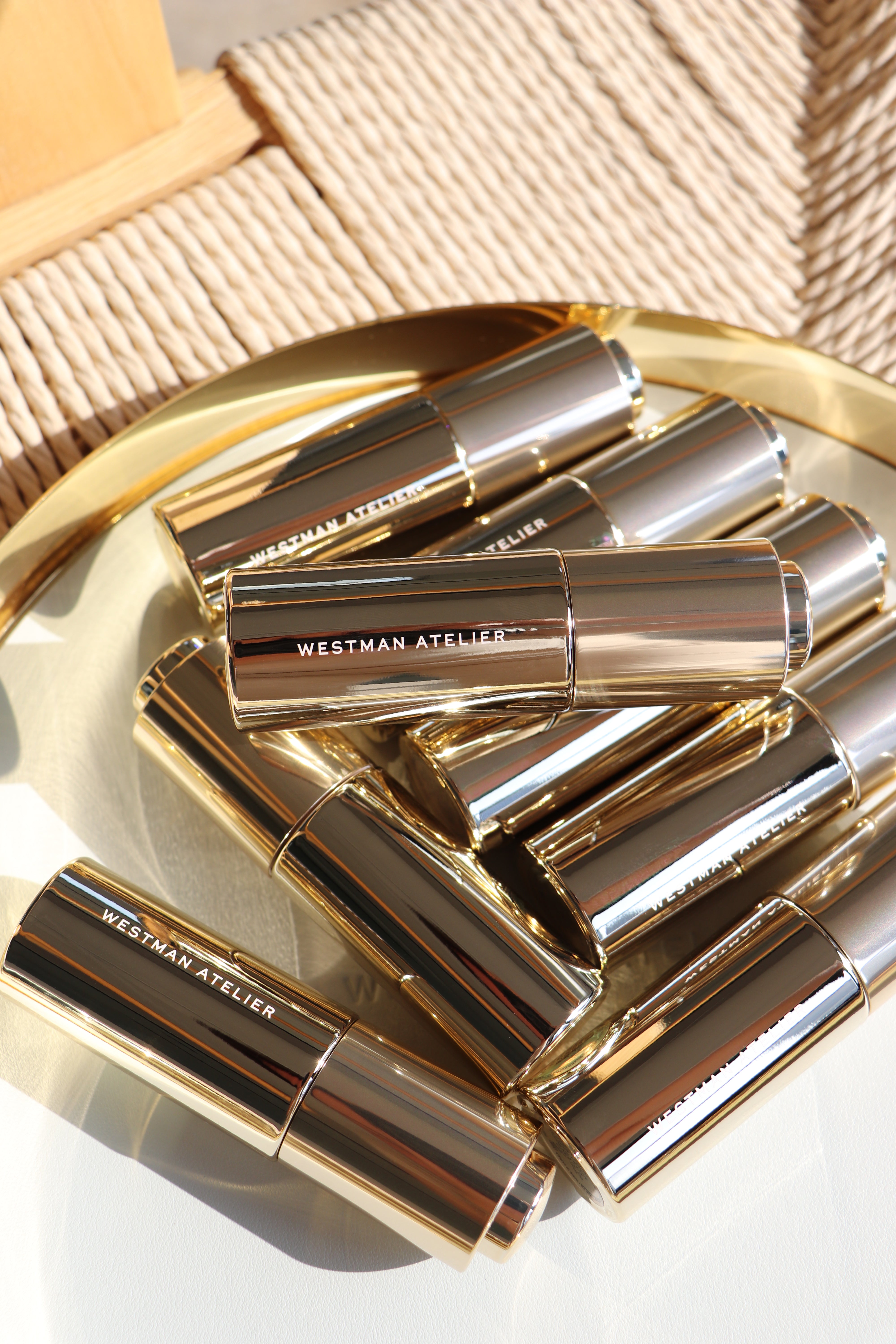 Multiple Westman Atelier Eye Activator Serum tubes arranged on a gold tray in natural sunlight.