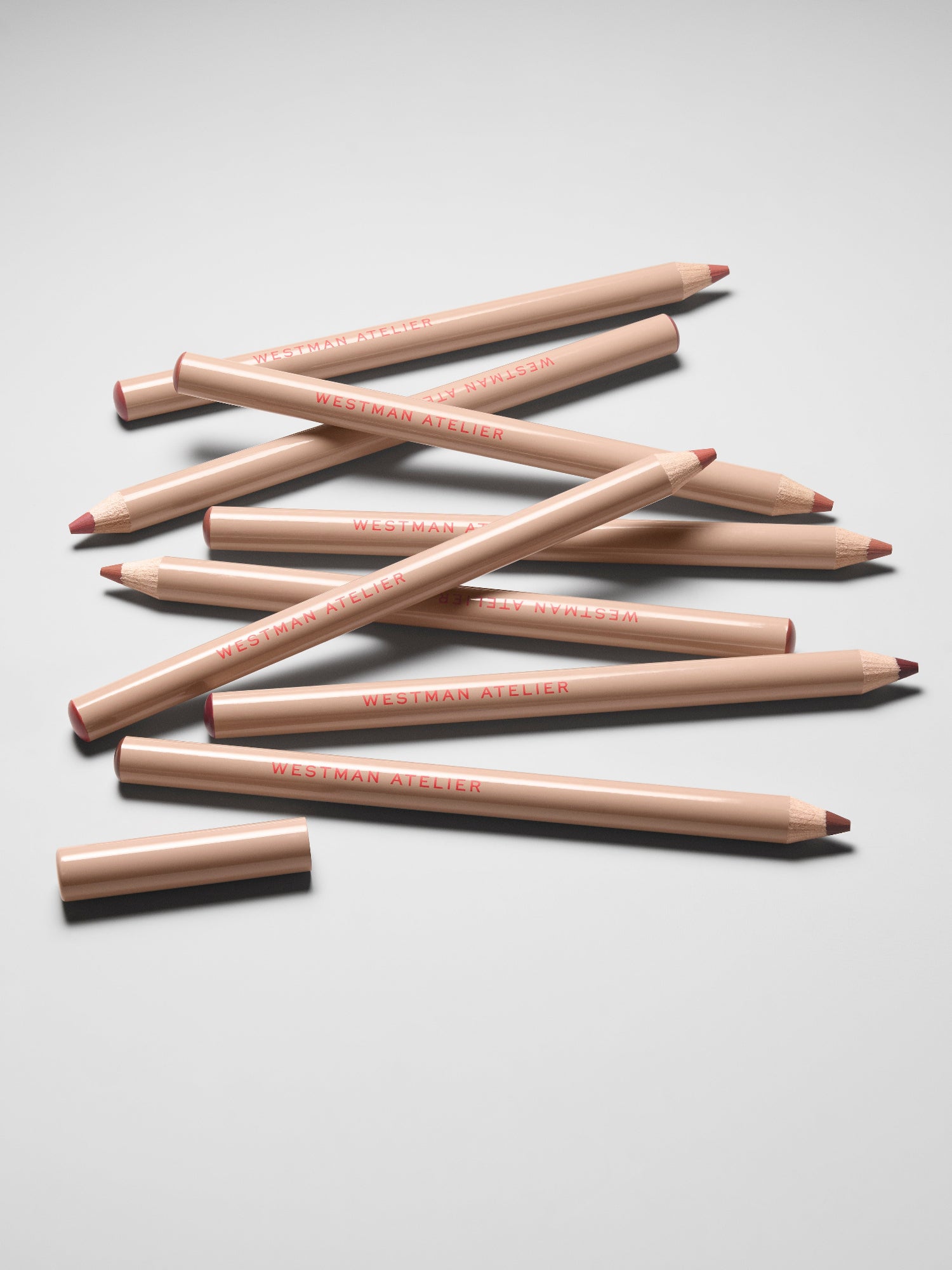 Westman Atelier Lip Shape Lip Liner pencils arranged on a light gray background.