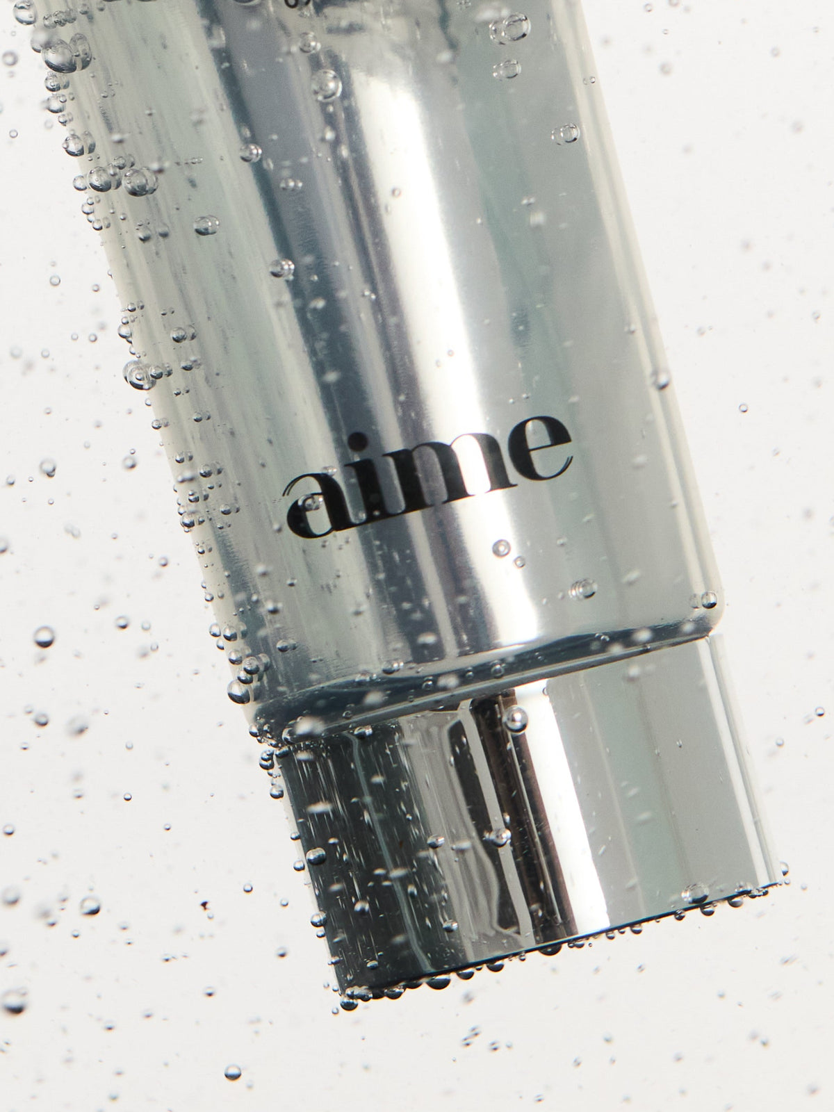 AIME The Cleansing Balm tube surrounded by water droplets