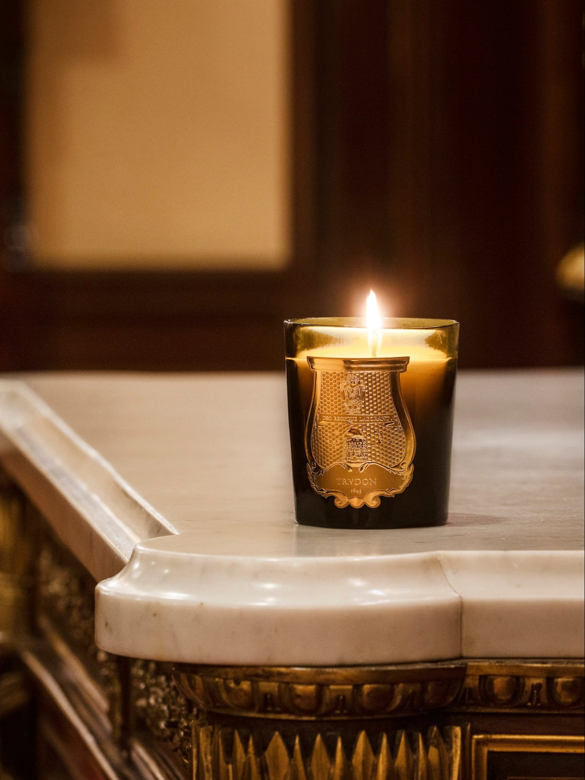 Cire Trudon Classic Candle 270g lit on a marble table in an elegant interior