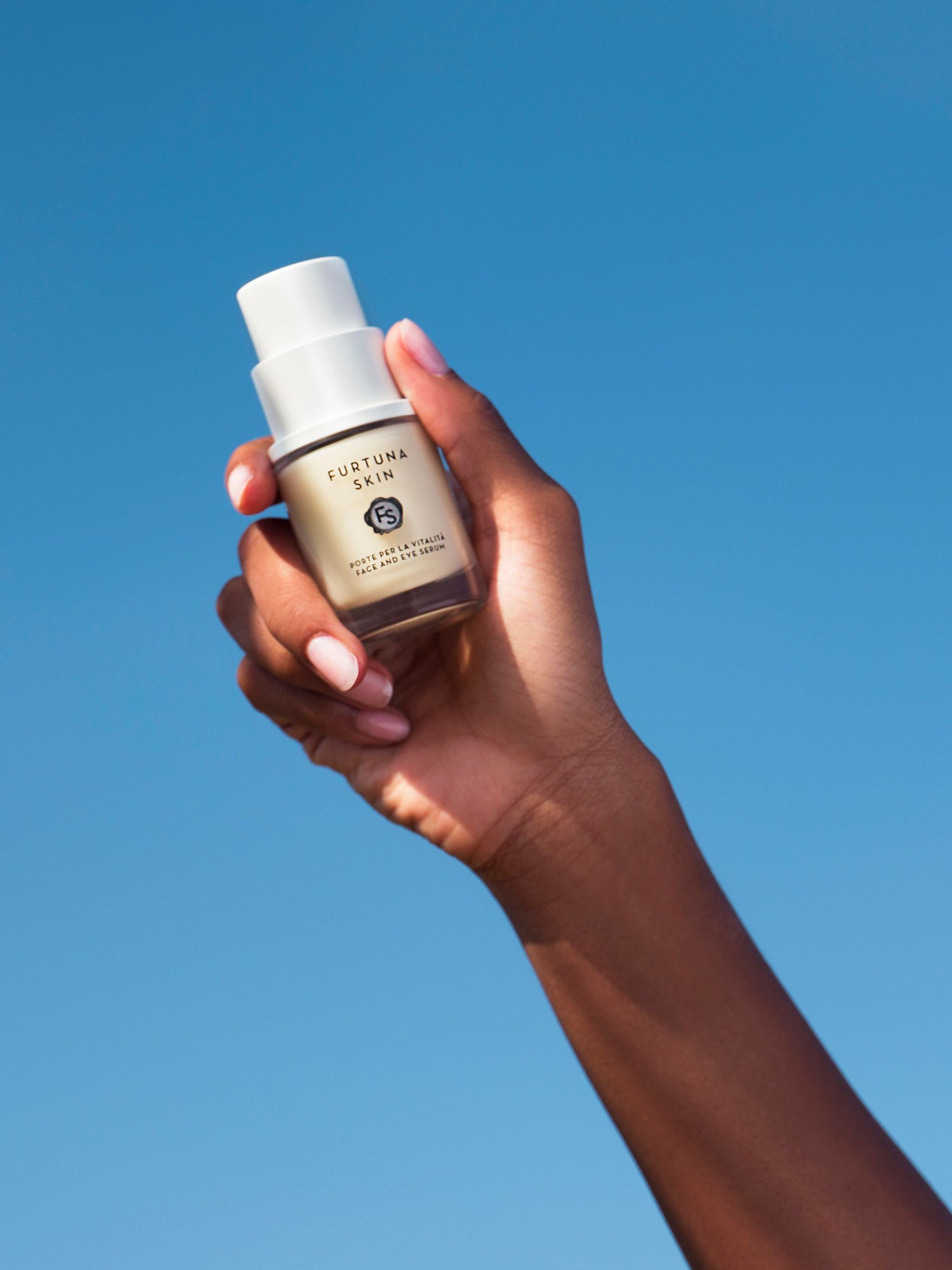 Furtuna Skin Porte Per La Vitalità Face and Eye Serum travel size held in hand against blue background
