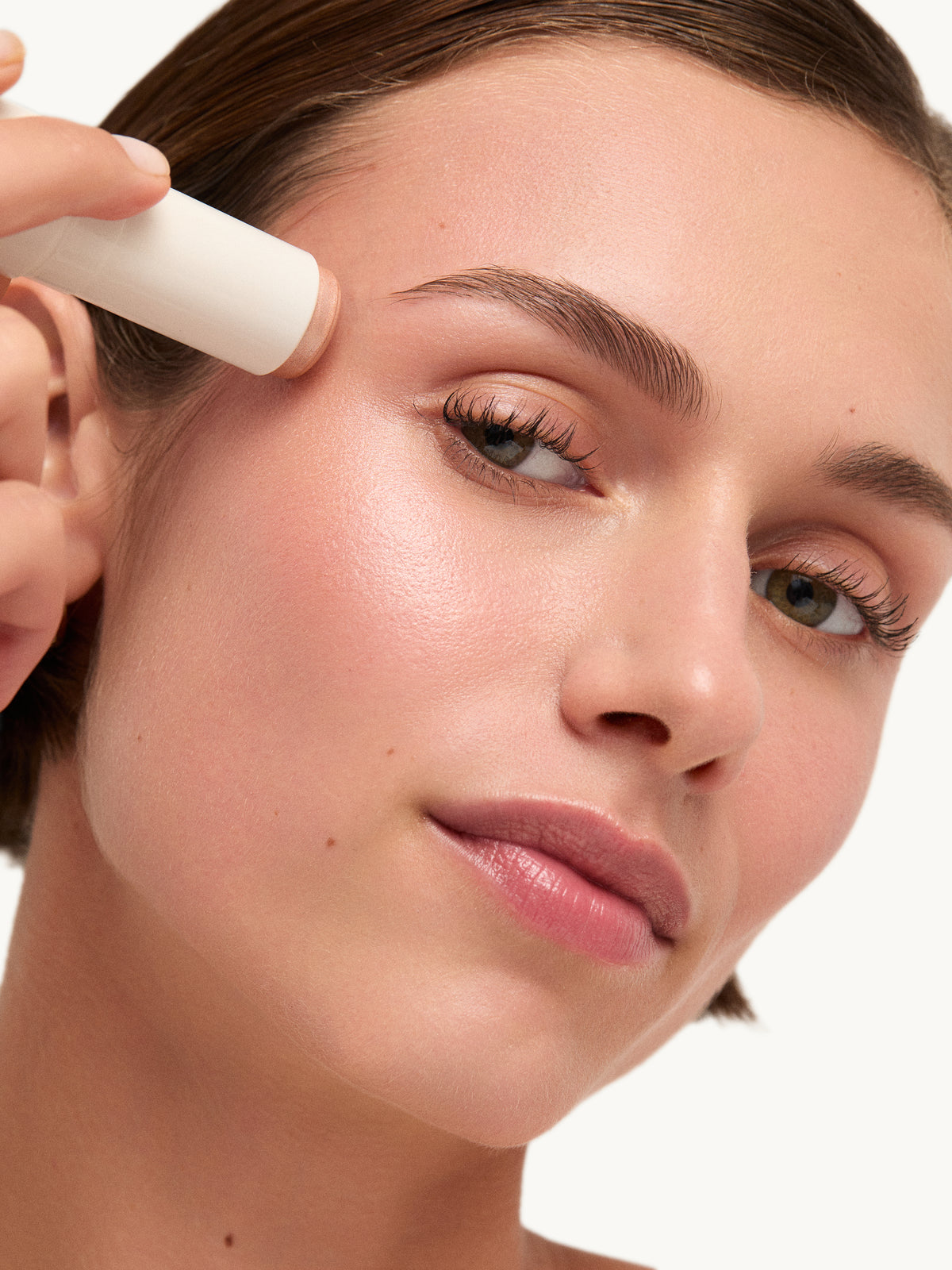 goop beauty Glow Skin Highlighter Stick in Aura applied to cheekbones