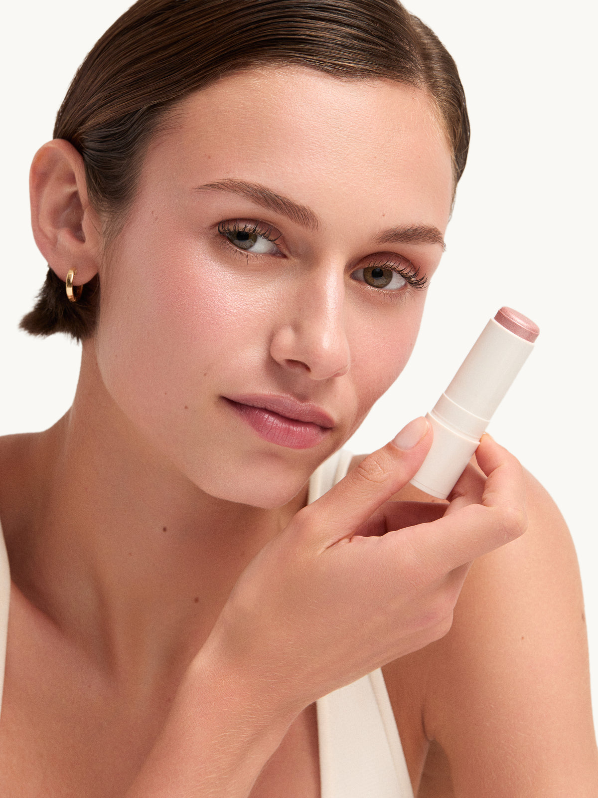 Model holding goop beauty Glow Skin Highlighter Stick in Petal