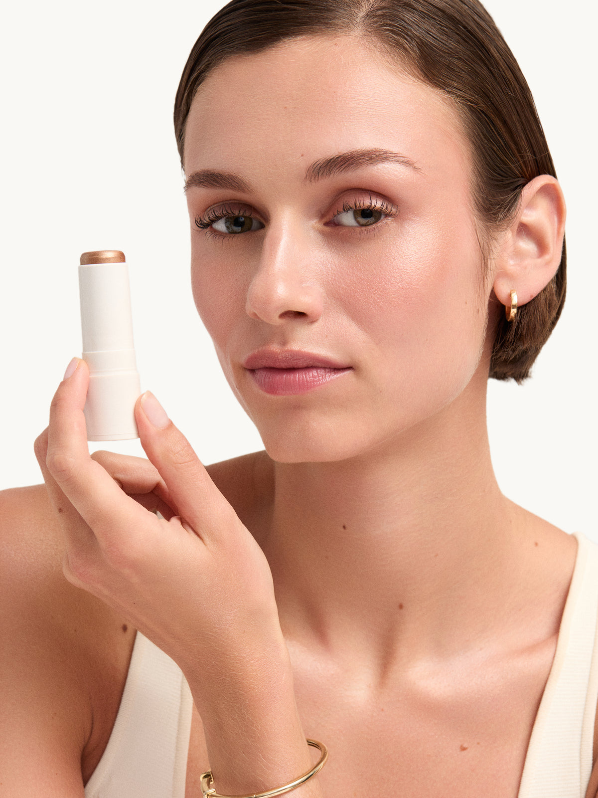 GOOP BEAUTY Glow Skin Highlighter Stick in Sunny held by a model