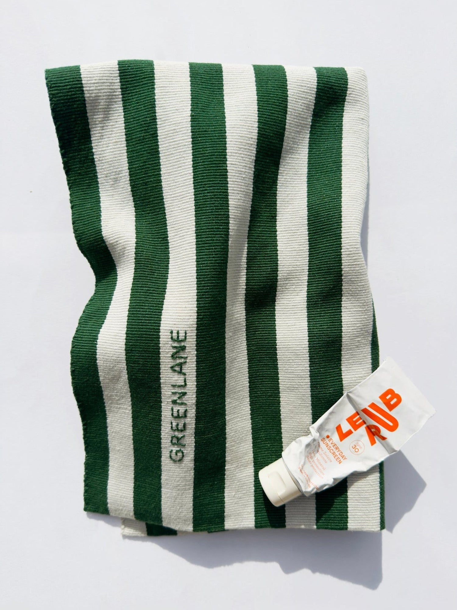 GREENLANE handwoven green and white striped tote bag with beauty product