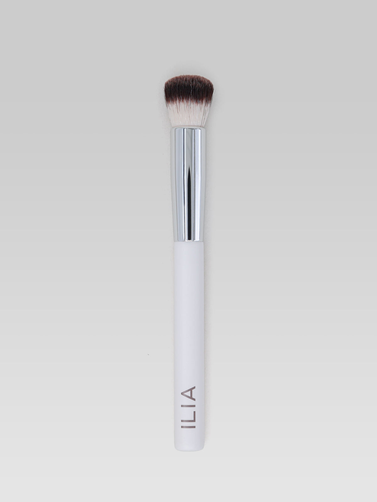 ILIA BEAUTY Complexion Brush with dense, rounded bristles, a silver ferrule and a white handle for smooth, even makeup application.
