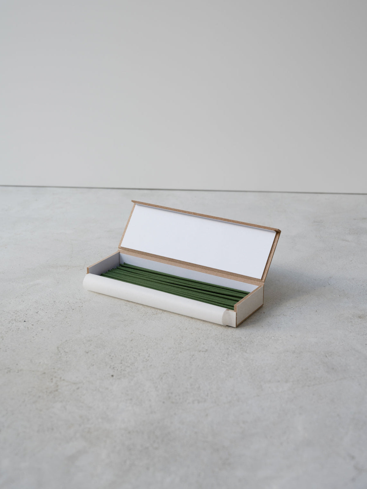 JJIMJIL Green Tea Incense Sticks neatly arranged in an open rectangular box on a light stone surface