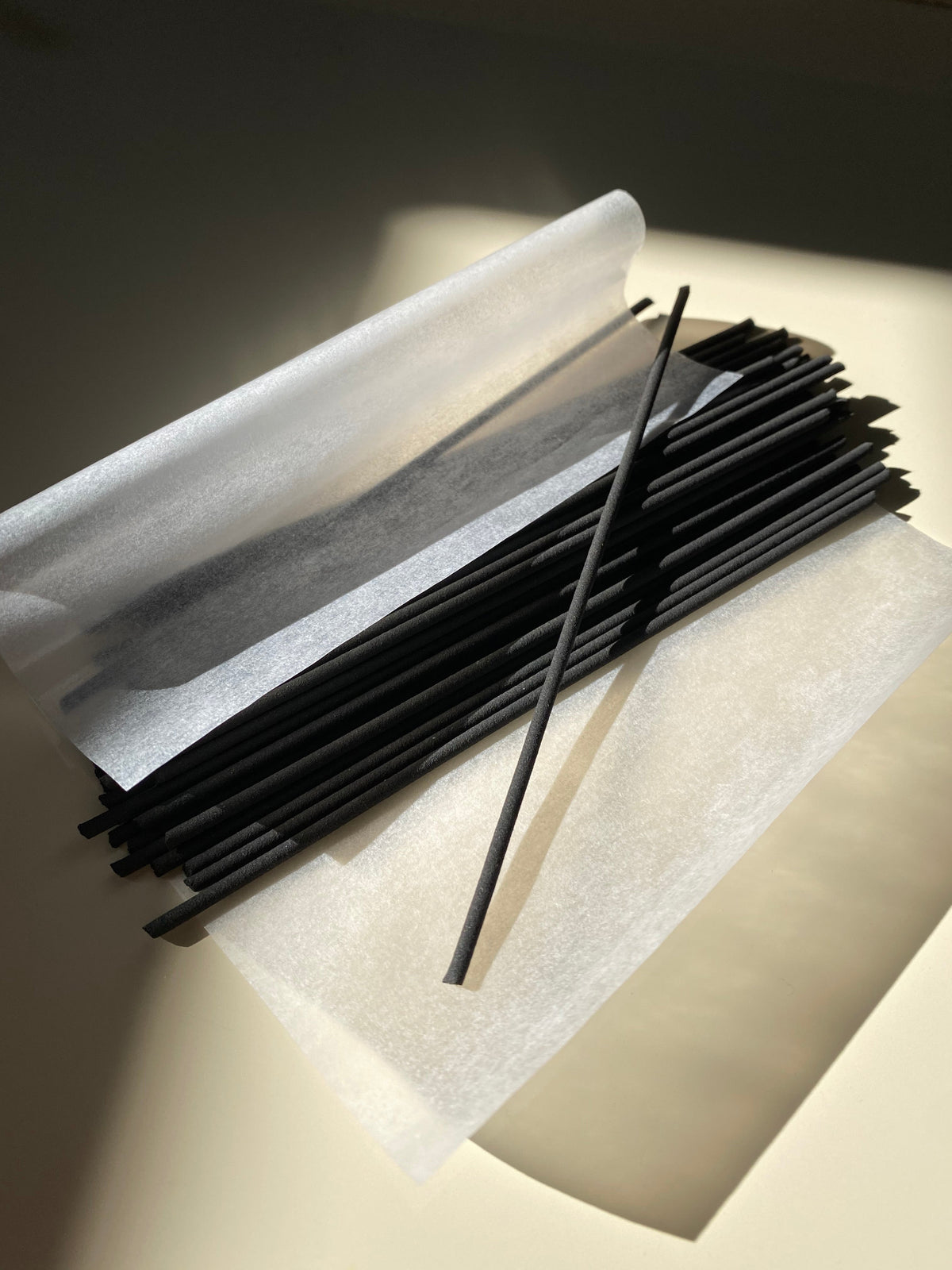 JJIMJIL black incense sticks arranged on translucent protective paper in warm natural light