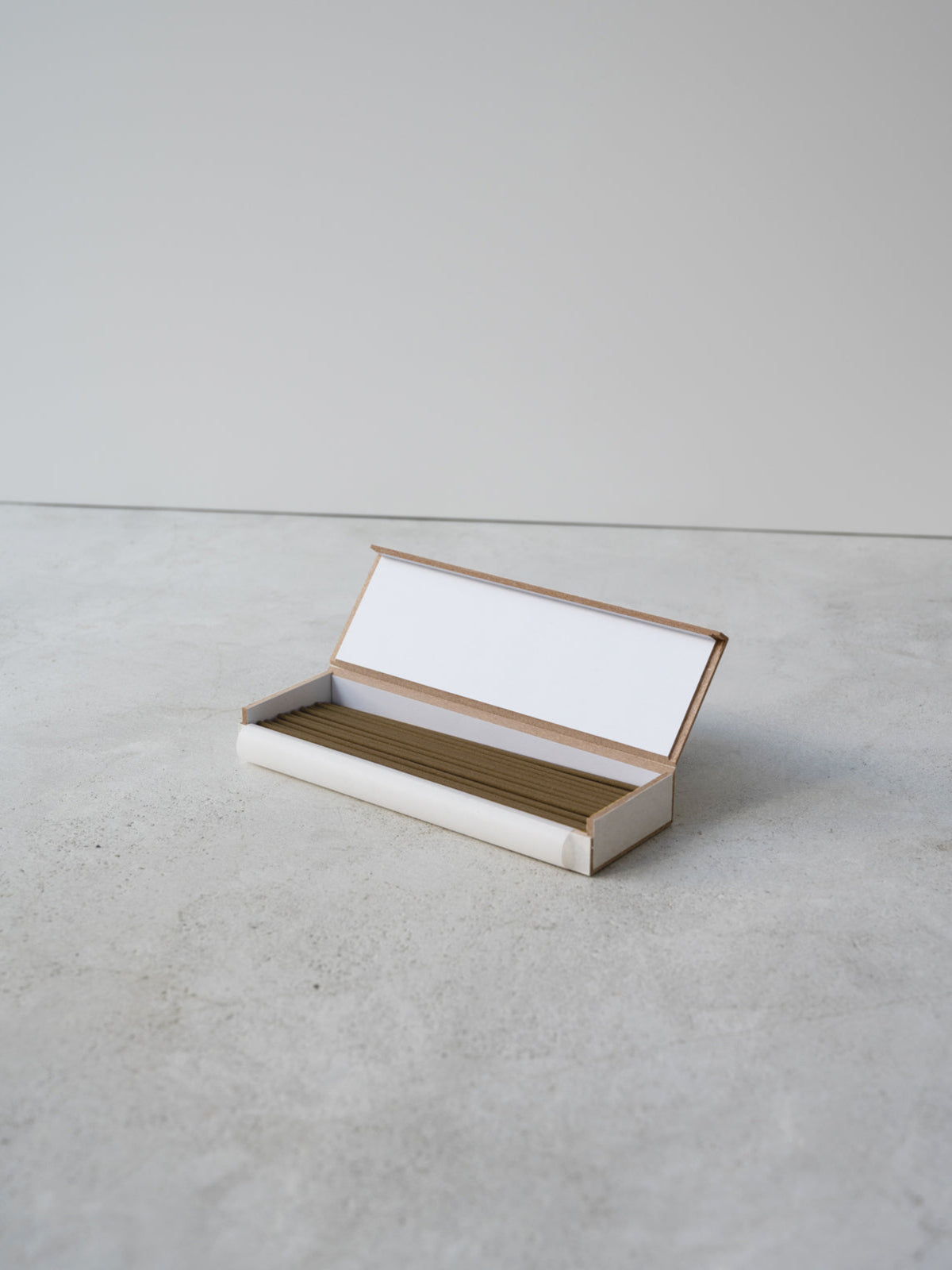 JJIMJIL Sandalwood Incense Sticks arranged in an open rectangular box on a light stone surface