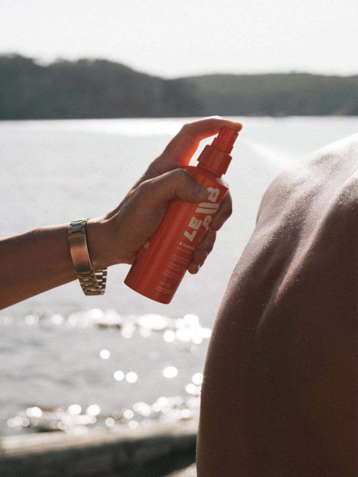 Applying LE RUB Sunscreen Mist SPF 50 to the body