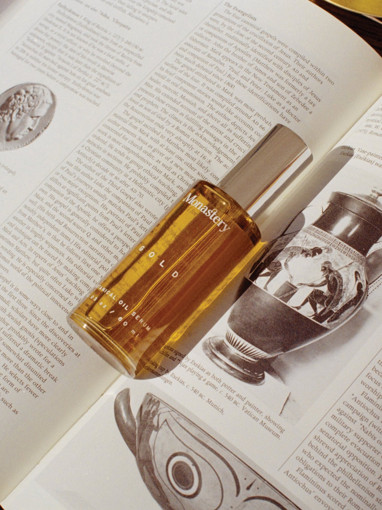 MONASTERY Gold Oil Serum bottle on an open book