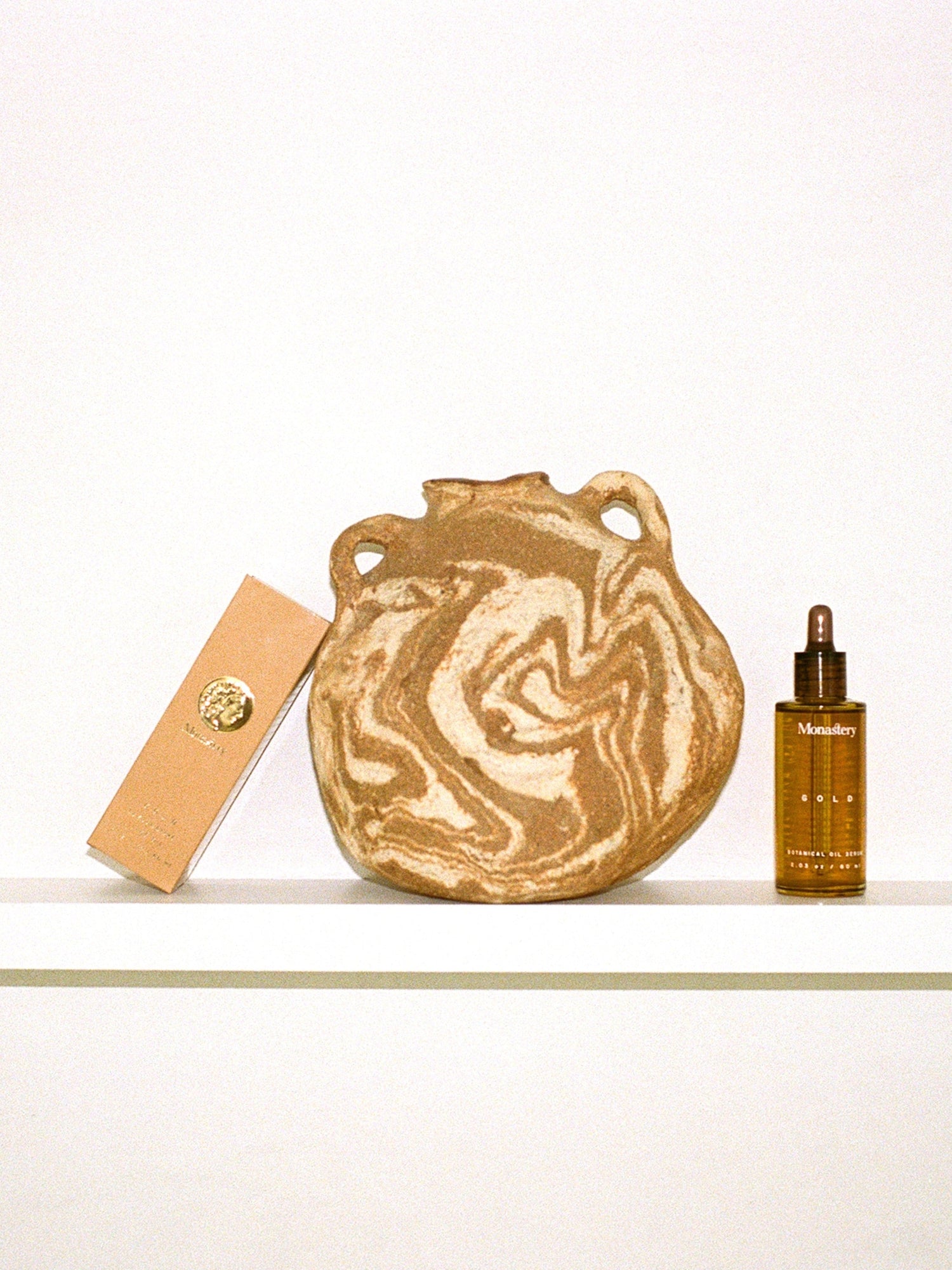MONASTERY Gold Oil Serum with packaging in an artistic still life
