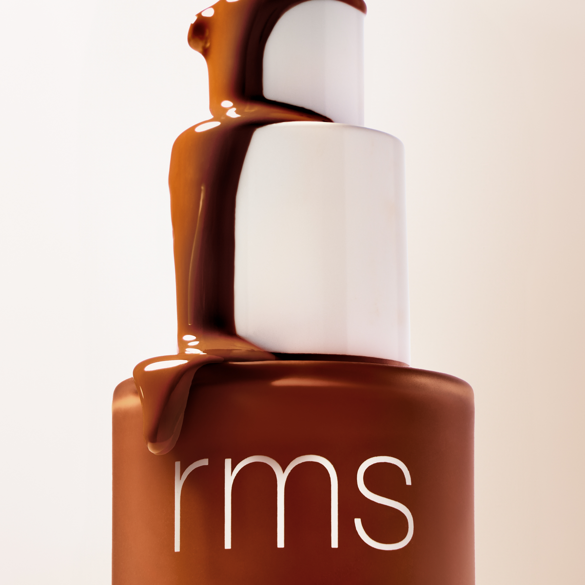 Woman demonstrating the application of RMS Beauty SunCoverup Super Tint SPF 50, a tinted moisturiser with broad-spectrum sun protection.