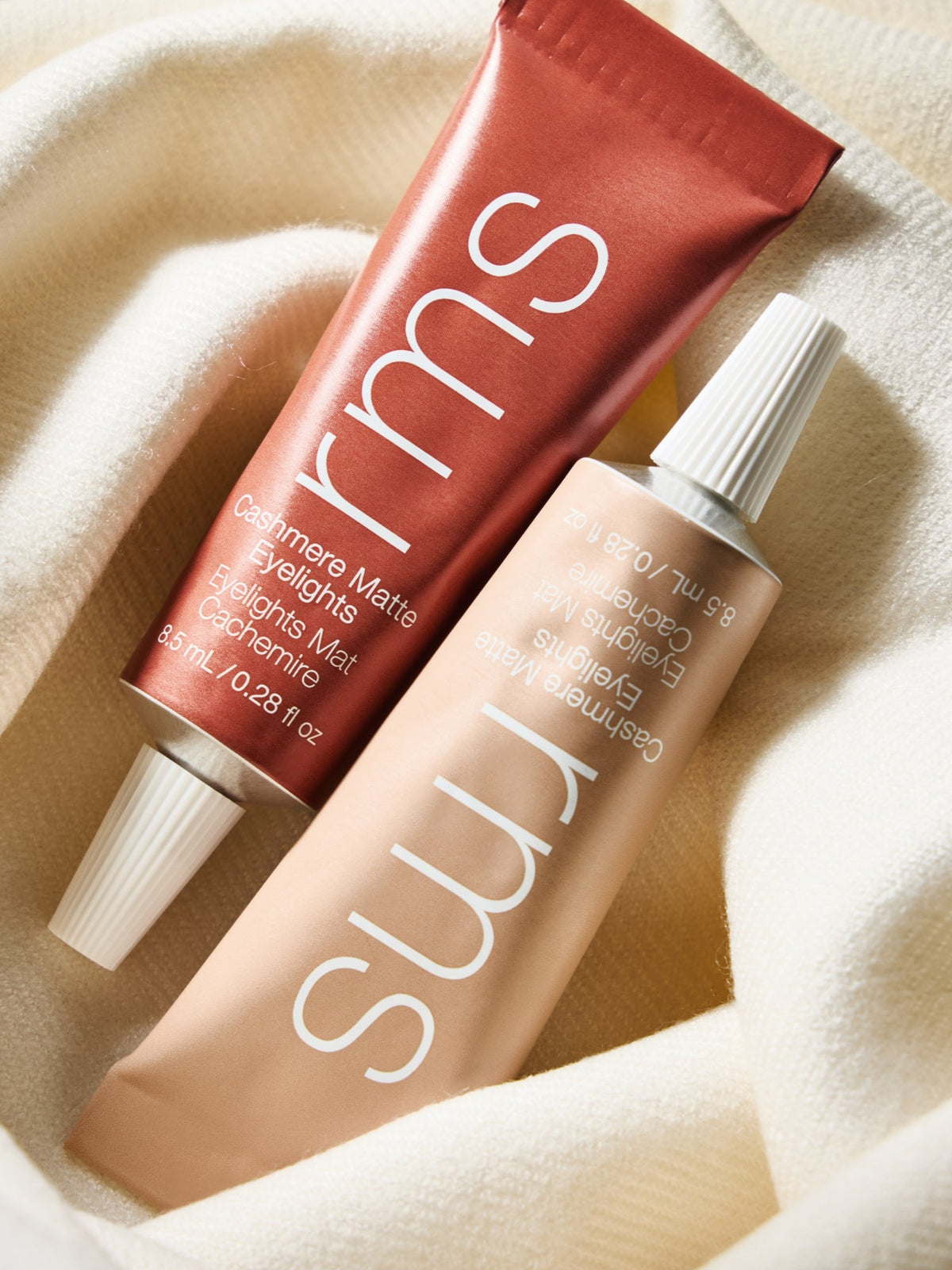 RMS Beauty Cashmere Matte Eyelights in warm terracotta and Tundra Taupe shades arranged on cream fabric