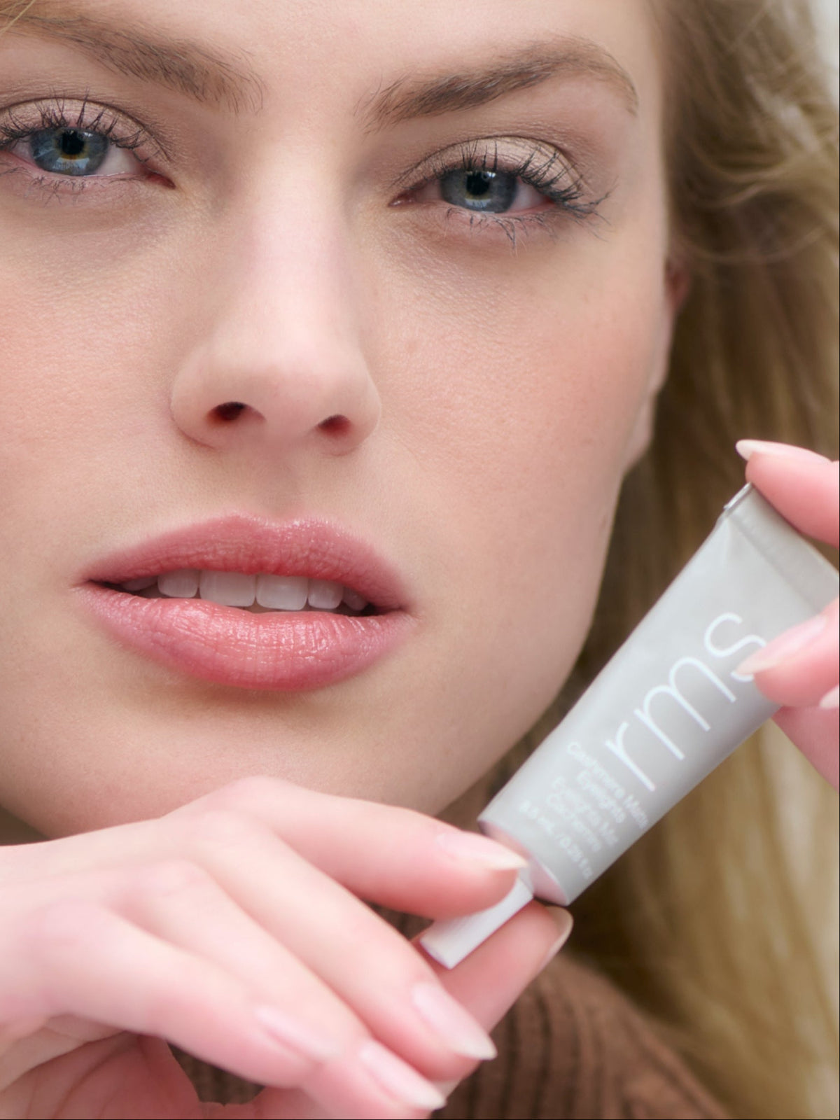 Model holding RMS Beauty Cashmere Matte Eyelights in Mountain Mist beside her face