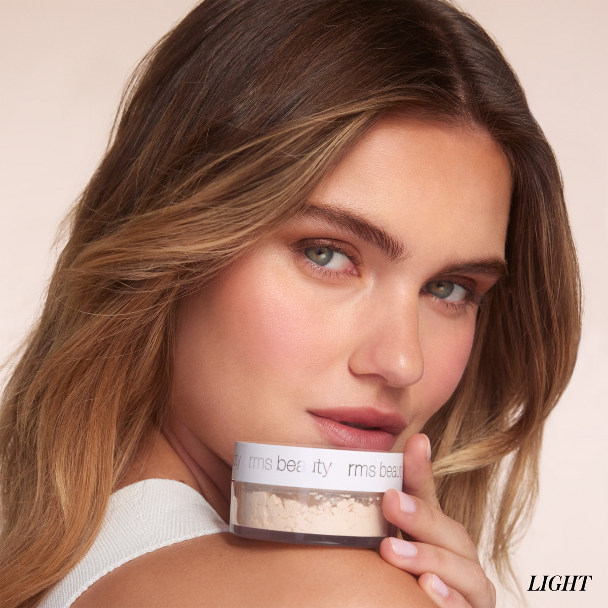 Model holding RMS Beauty Hydra Setting Powder in Light shade