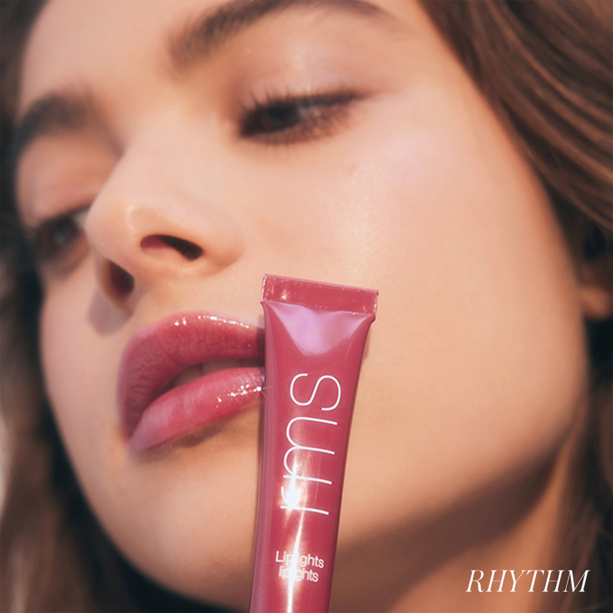 Model wearing RMS Beauty LipLights Cream Lip Gloss in Rhythm, showcasing glossy berry-pink lips