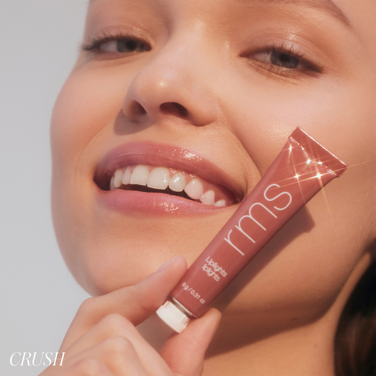 Model wearing RMS Beauty Lip Lights Cream Lip Gloss in Crush, showing glossy coral-pink lips