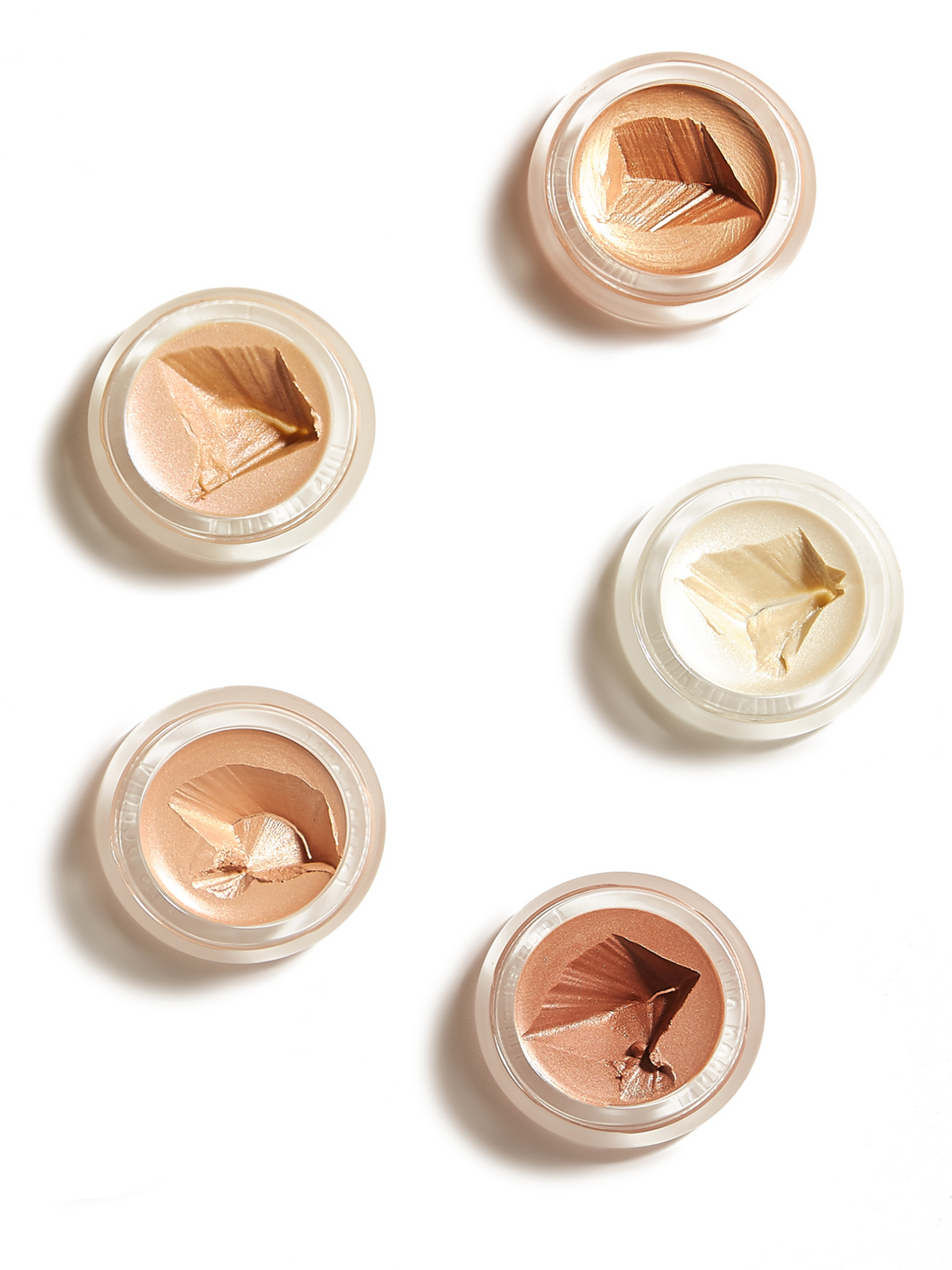 Five RMS Beauty luminizers in open round pots, showcasing a range of champagne, golden, peach and bronze highlighting shades on a white background