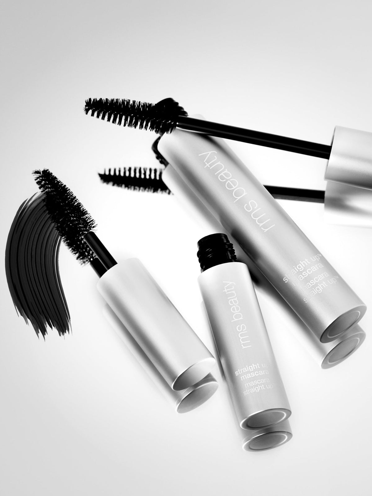 RMS Beauty Straight Up Volumizing Peptide Mascara tubes and open wands with black mascara brushes, displayed on a white background