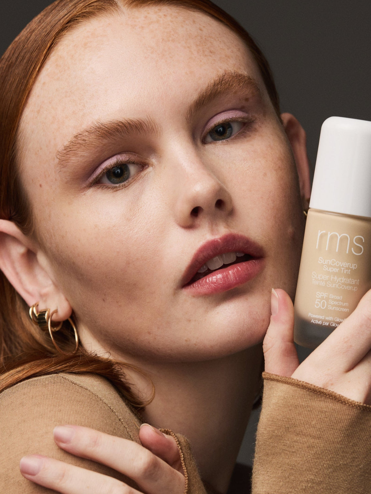 Model holding RMS Beauty SunCoverup Super Tint SPF 50 in Alabaster beside her face