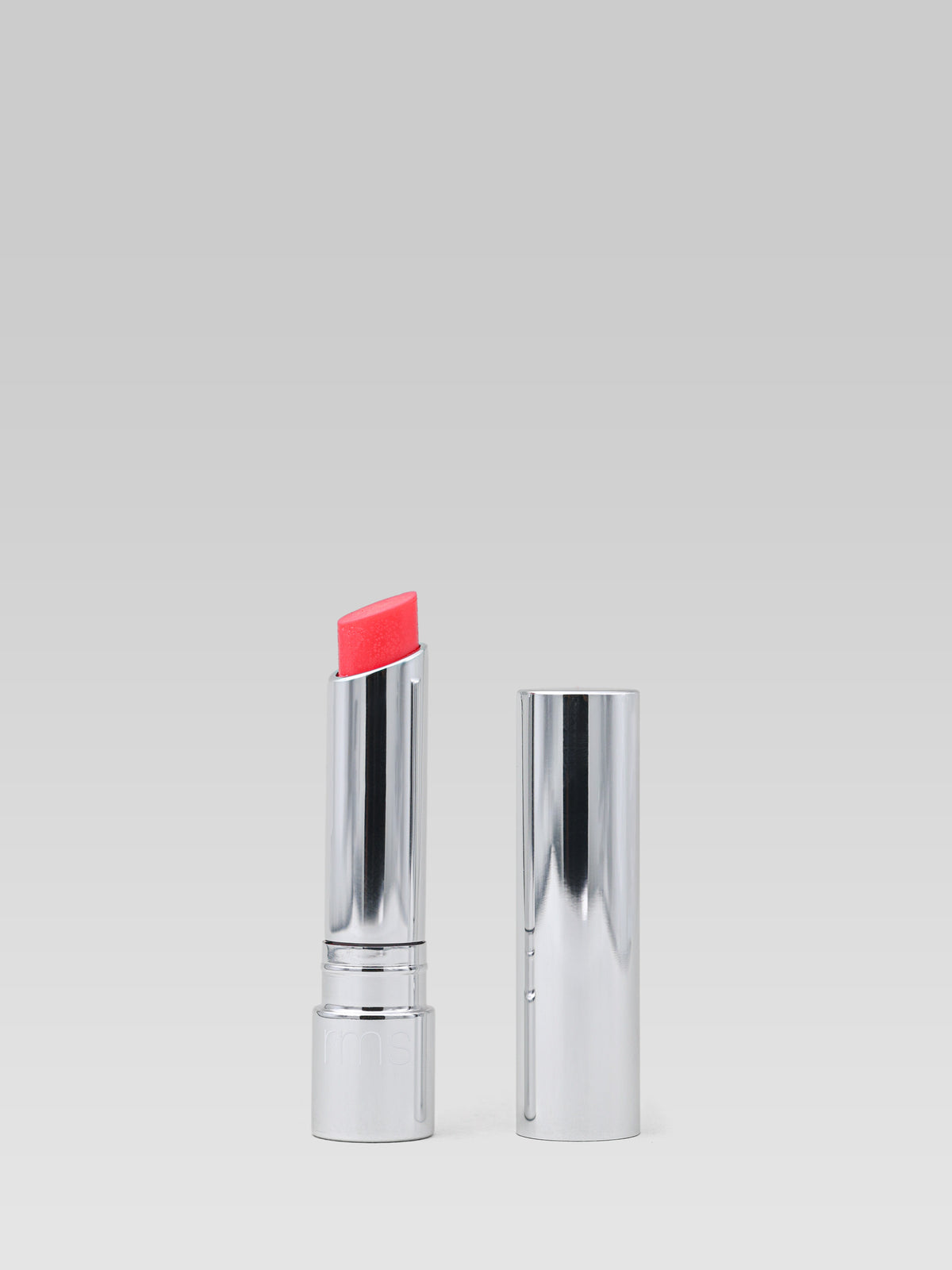 RMS Beauty Tinted Daily Lip Balm in Peacock Lane, vibrant pink-red tinted lip balm in silver packaging with cap displayed beside the open tube