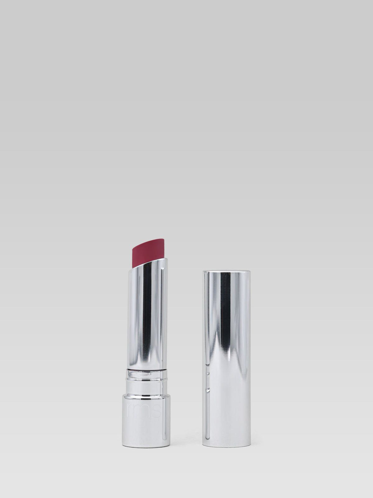 RMS Beauty Tinted Daily Lip Balm in Twilight Lane, deep berry-plum tinted lip balm in a silver tube with the cap removed, shown on a light grey background