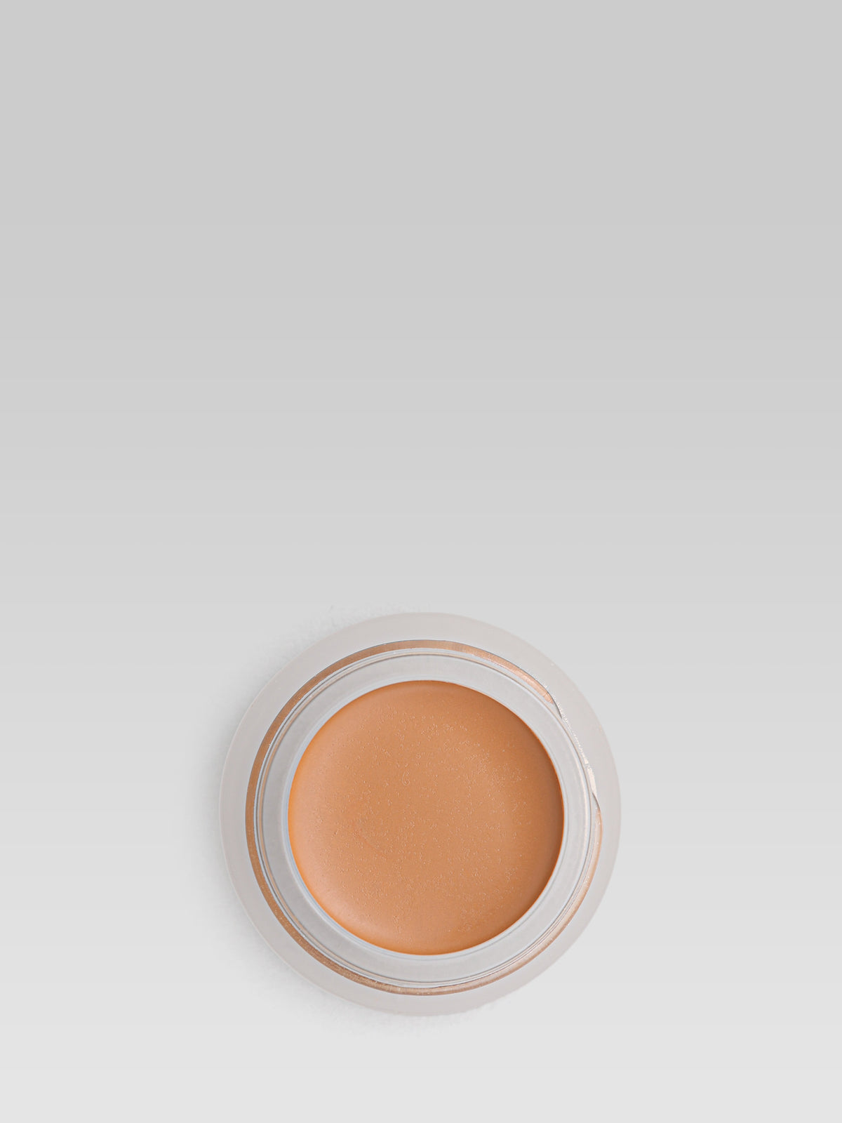 RMS Beauty UnCoverup Concealer in shade 55, shown in an open round pot with a warm deep caramel-brown cream concealer against a light grey background