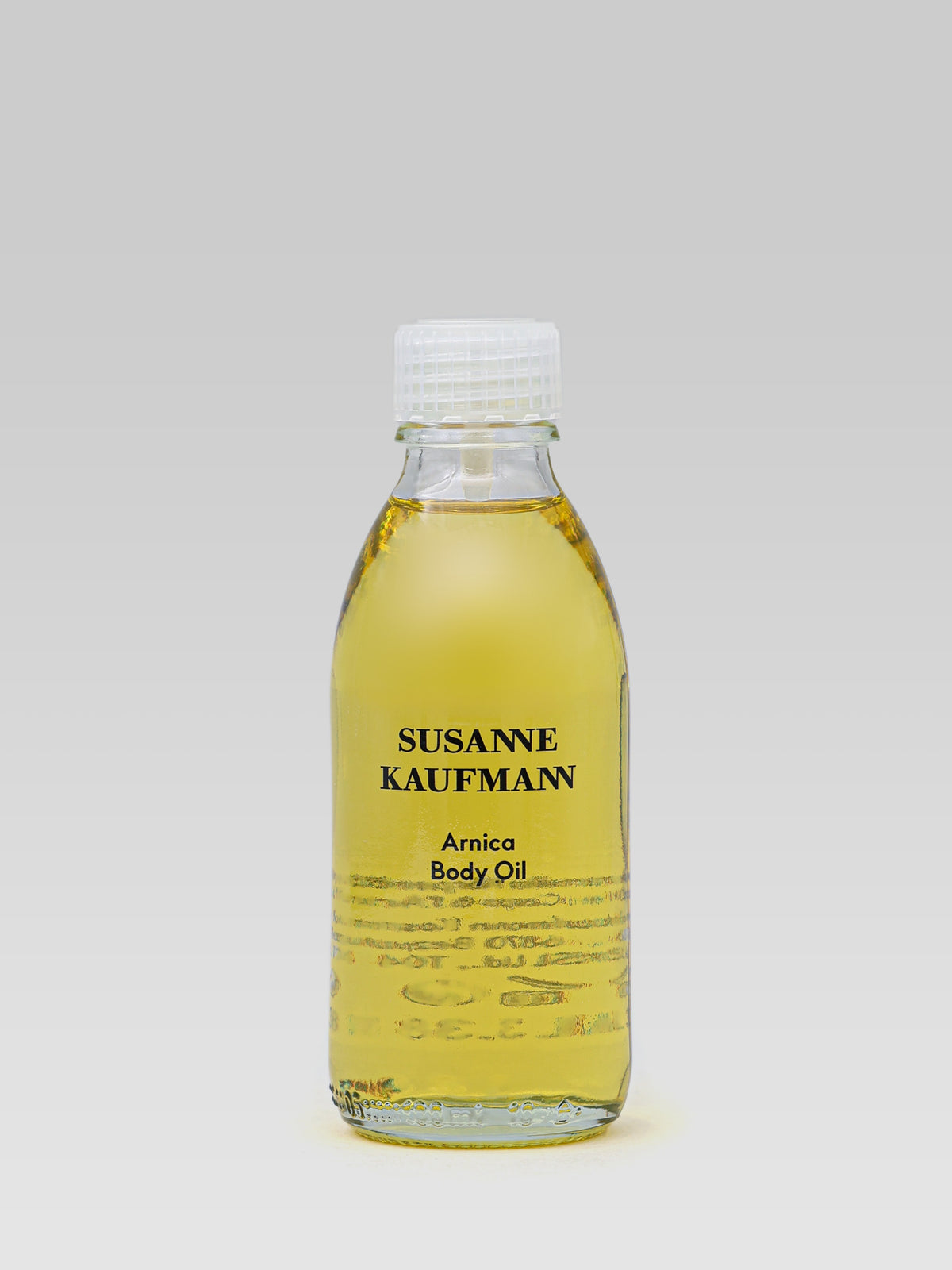 SUSANNE KAUFMANN Arnica Body Oil in a clear glass bottle with golden body oil