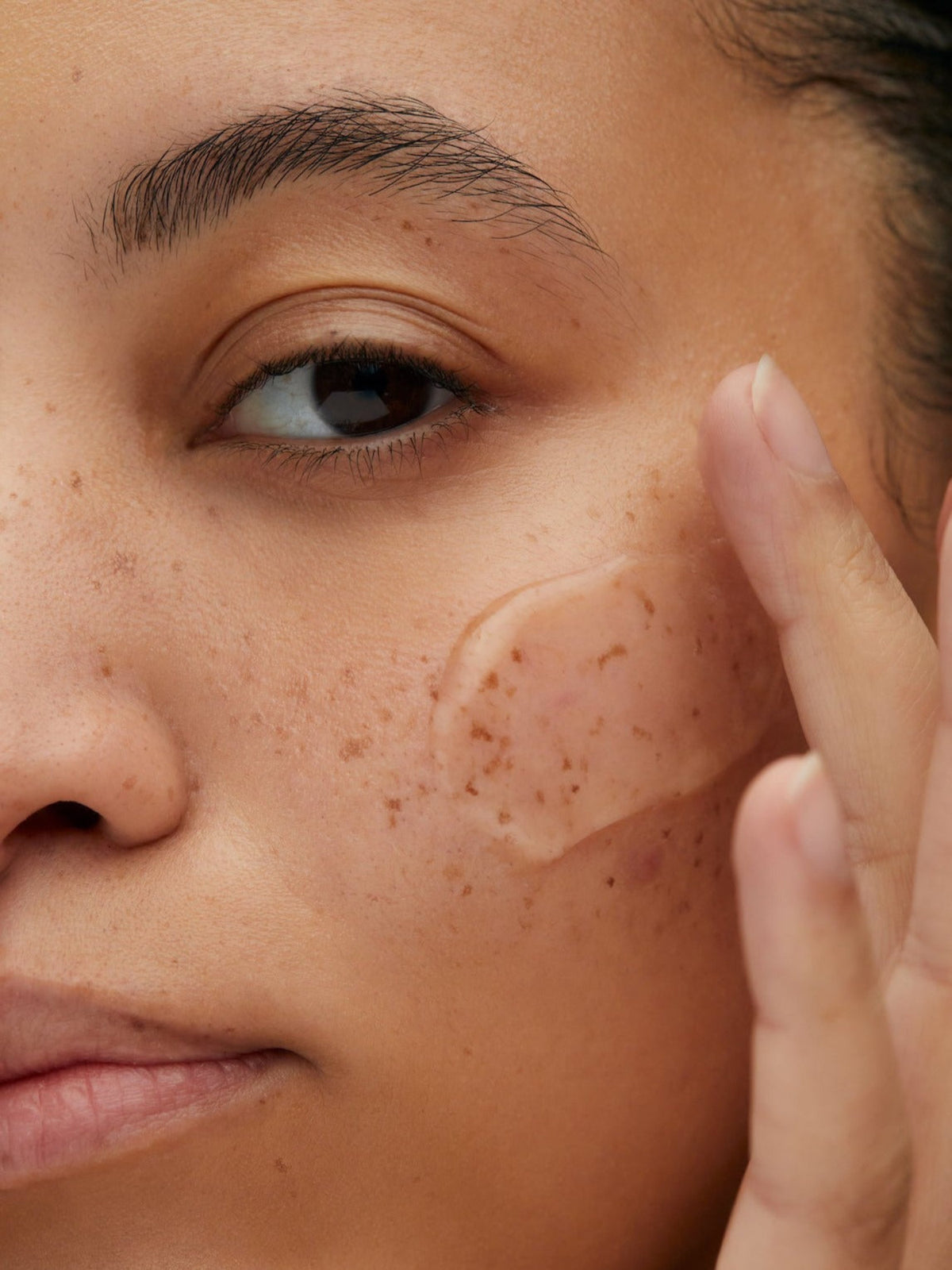 Close-up of a woman applying Susanne Kaufmann Enzyme Exfoliator to her cheek