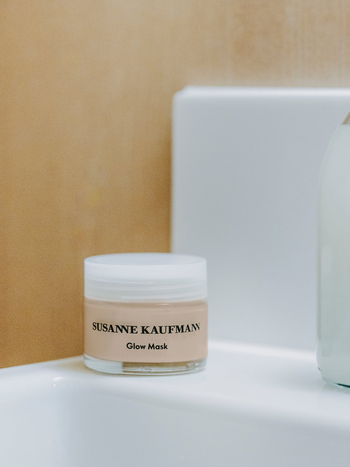 Susanne Kaufmann Glow Mask jar displayed on a white surface against a warm beige background