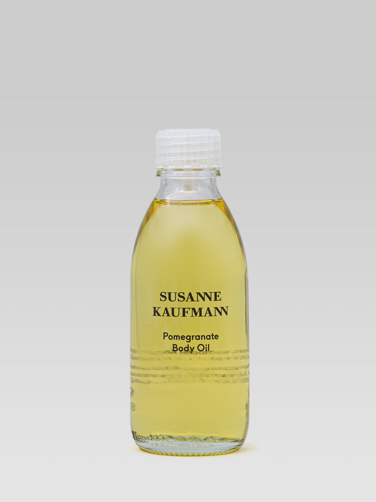 Susanne Kaufmann Pomegranate Body Oil 100 ml in a clear glass bottle with golden body oil against a light grey background